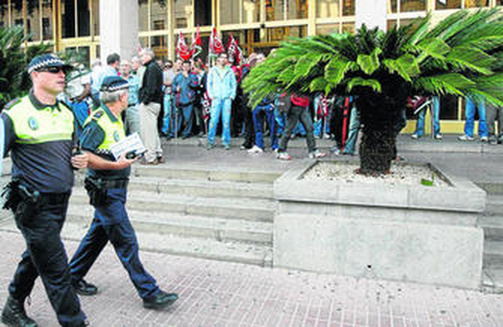 Dos agentes de la Policía Local pasan delante del Ayuntamiento, ocupado por sindicalistas que impiden el paso a los trabajadores municipales.