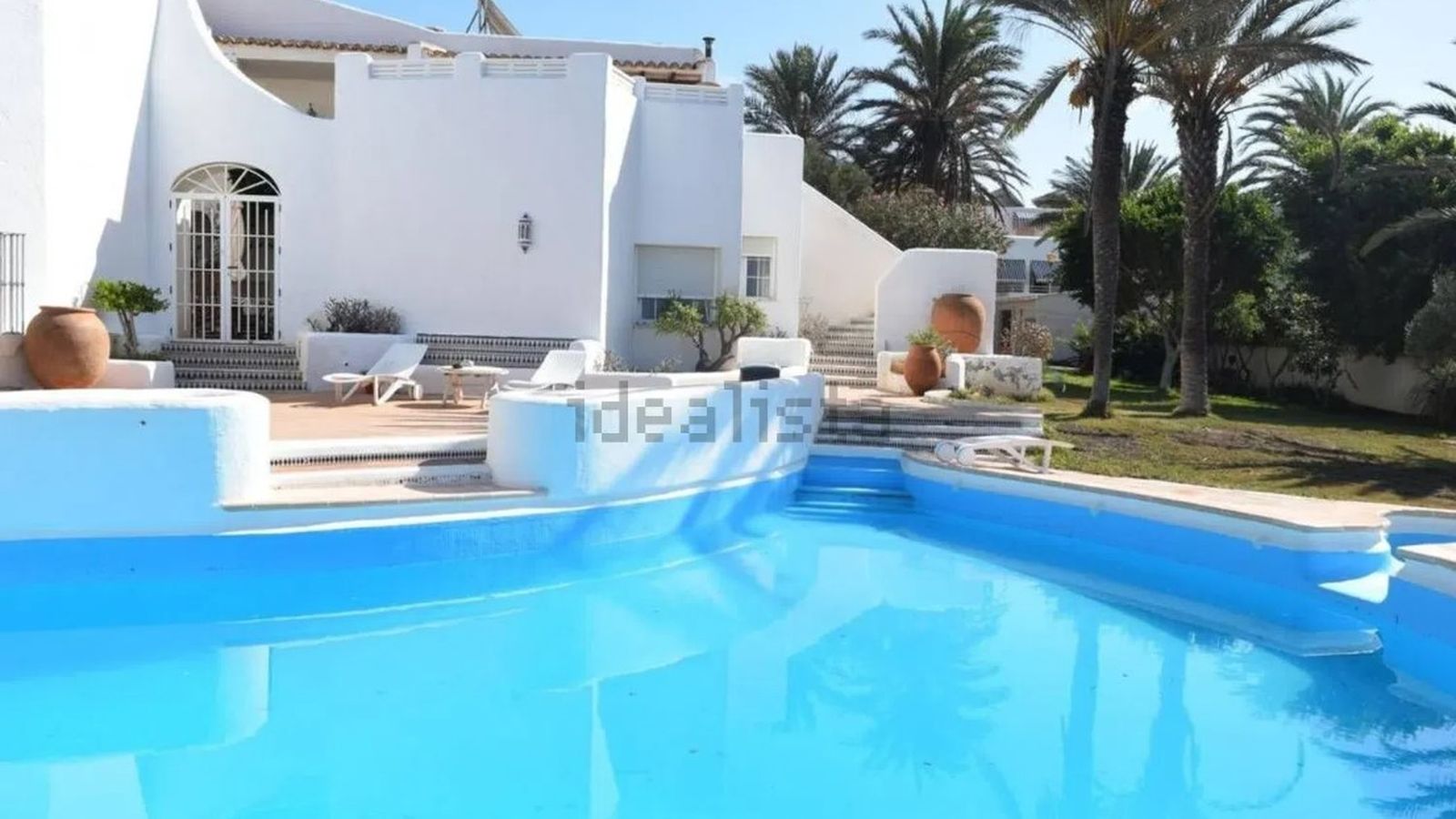 Vista general de la piscina con la vivienda principal al fondo, situada sobre una parcela elevada junto al campo de golf de Almerimar.