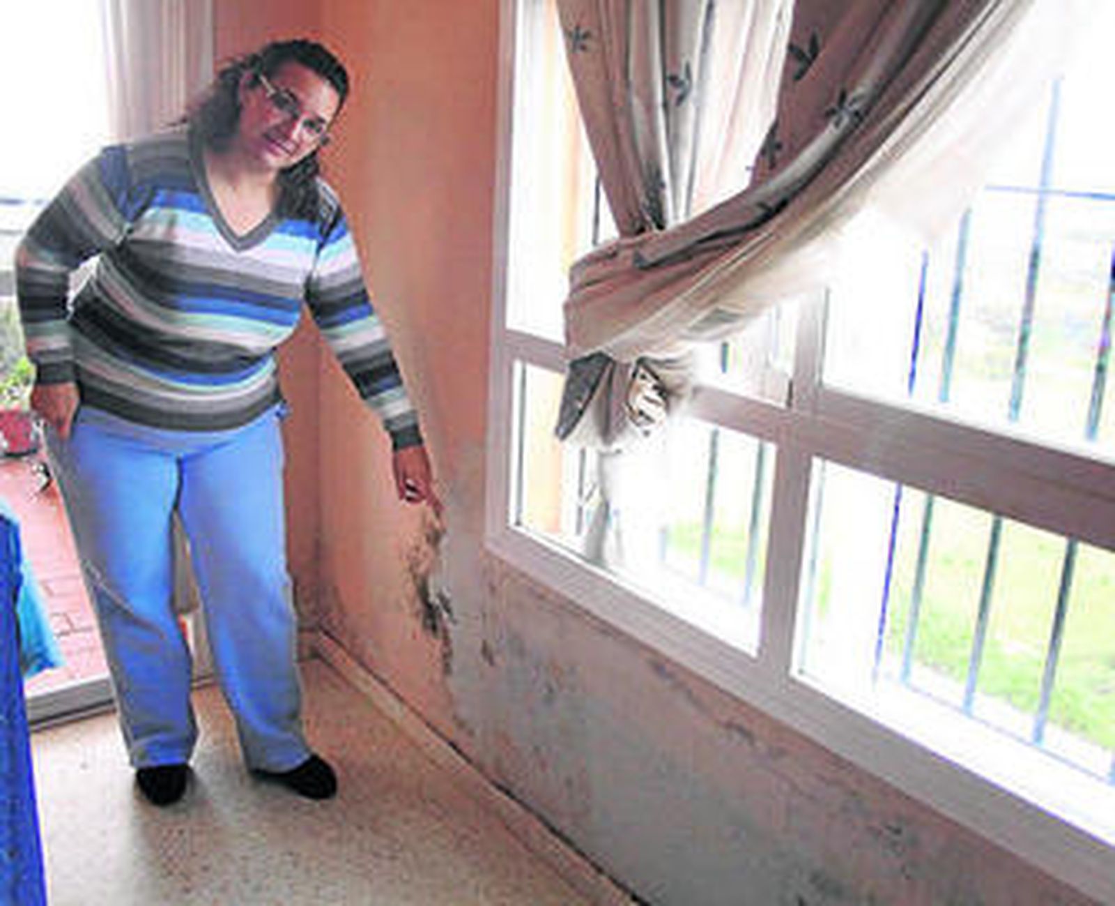 Una afectada muestra el deterioro de la pared y la humedad.