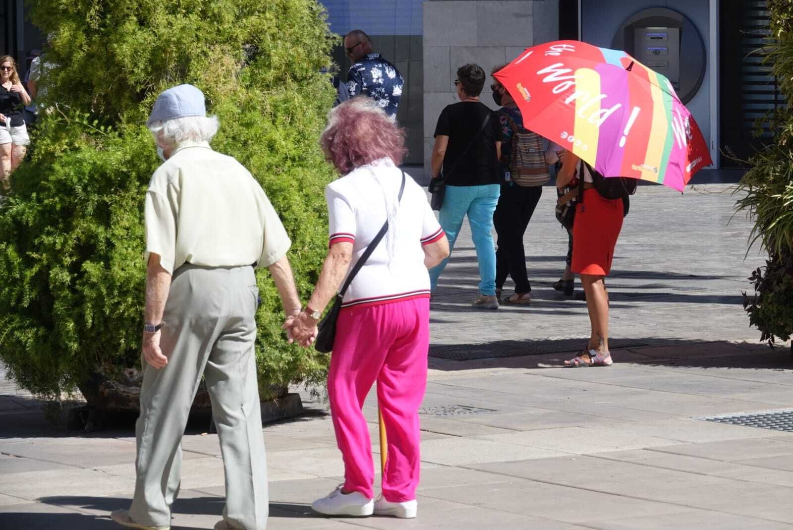 Una pareja de ancianos camina por calle Larios.