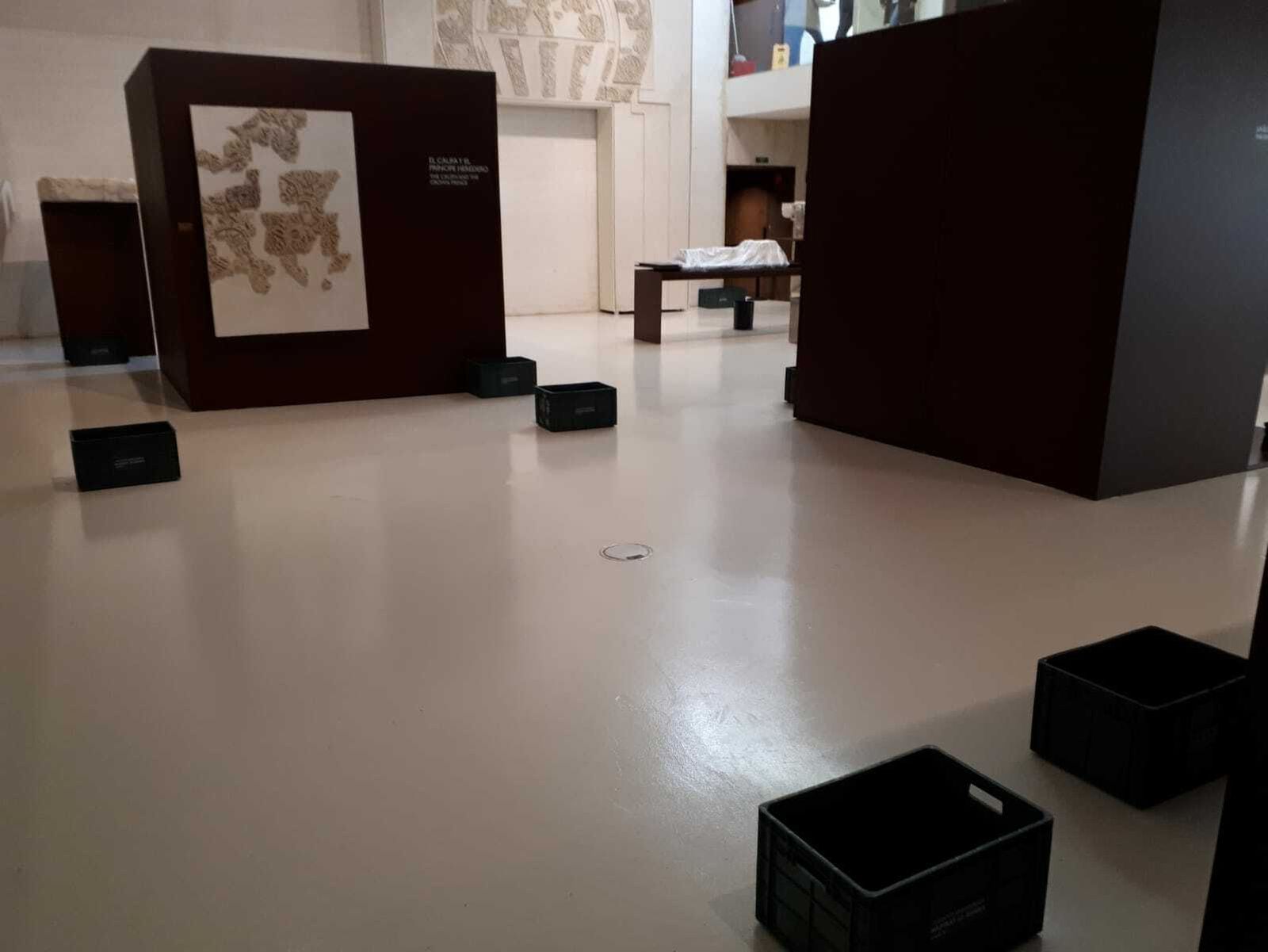 Piezas cubiertas con plásticos y cubos para recoger el agua en la sala expositiva de Medina Azahara.