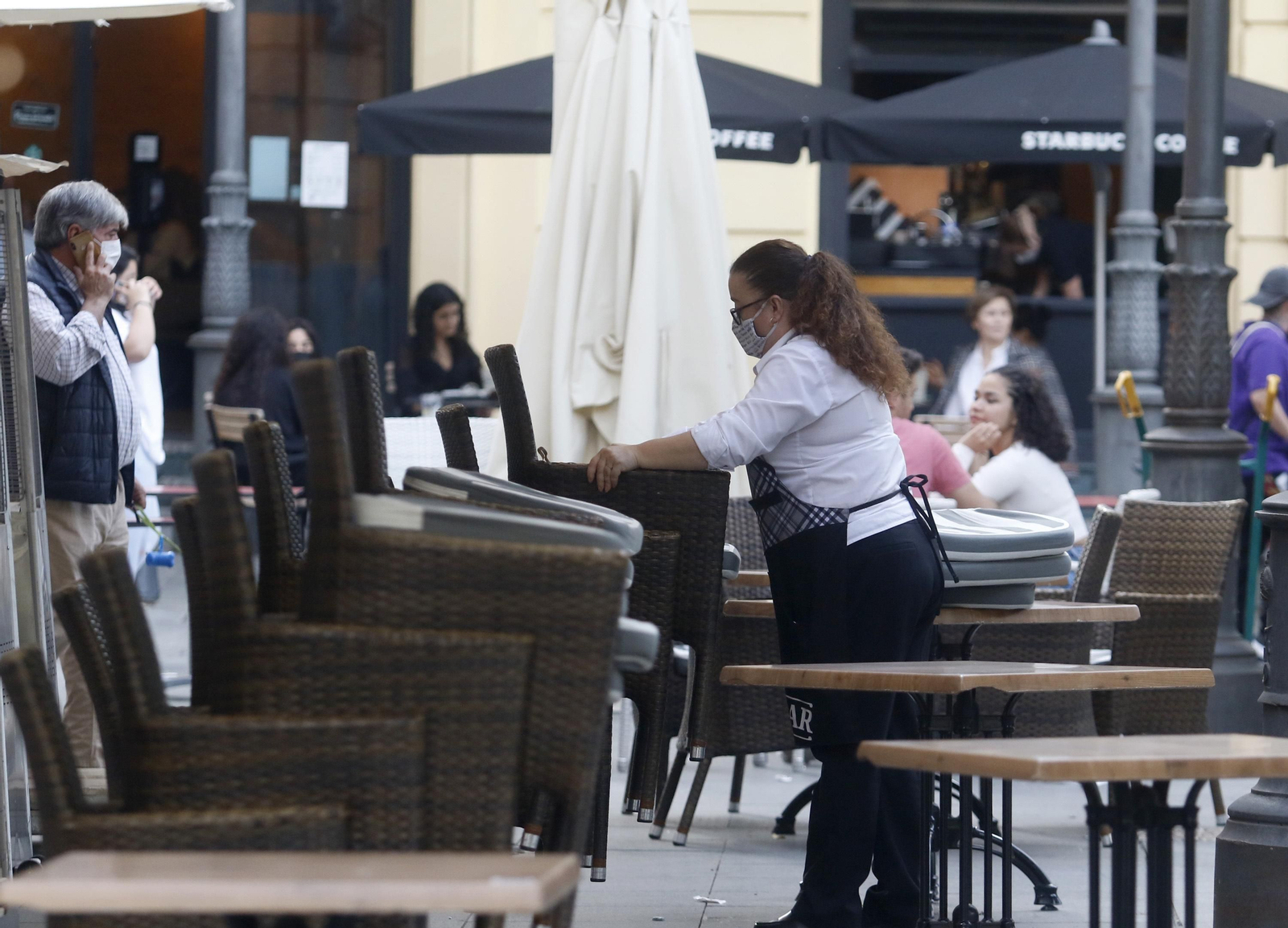 Una camarera recoge una terraza.