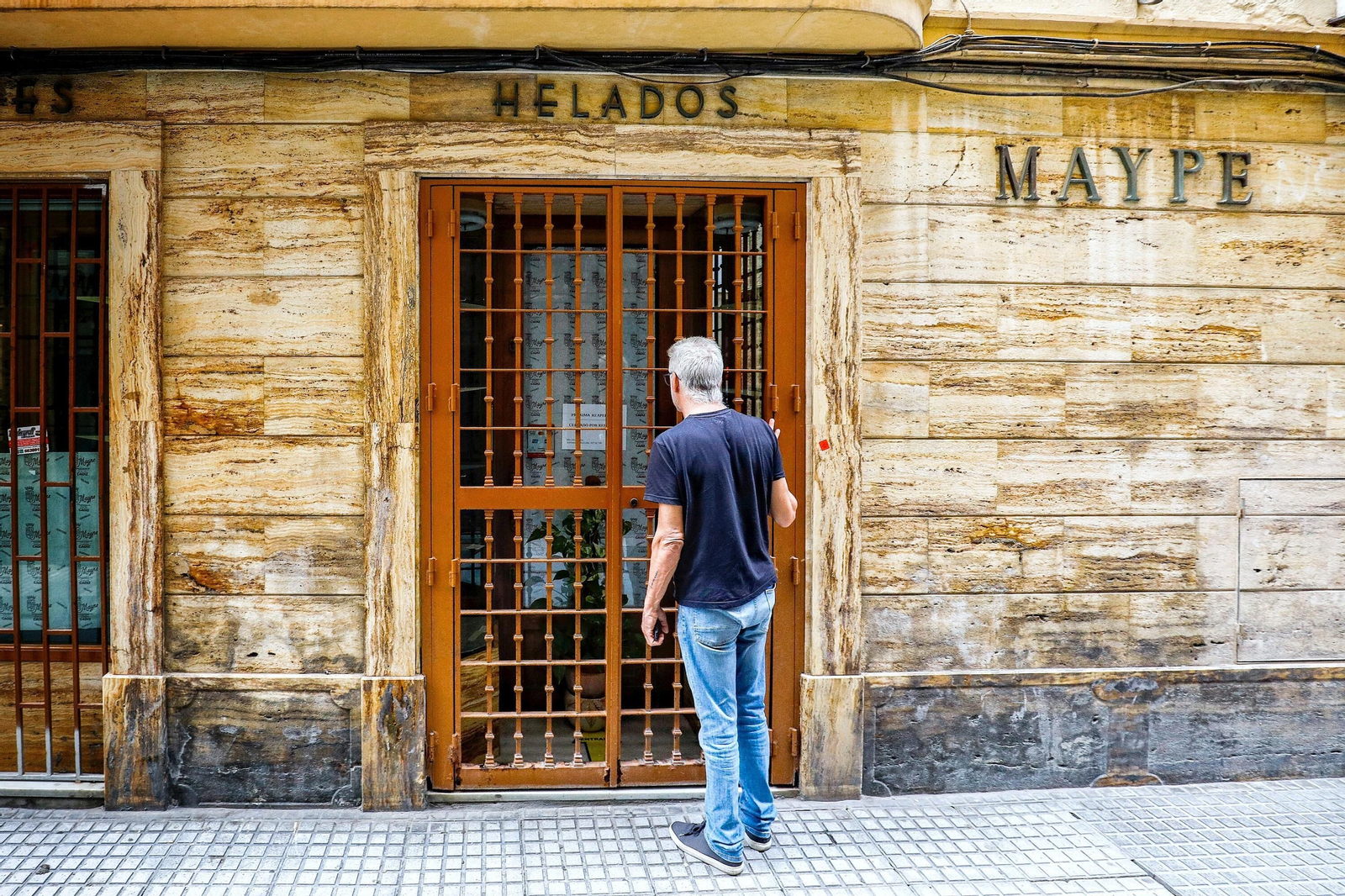 Un hombre lee el cartel que anuncia el cierre por reformas de la histórica confitería Maype.