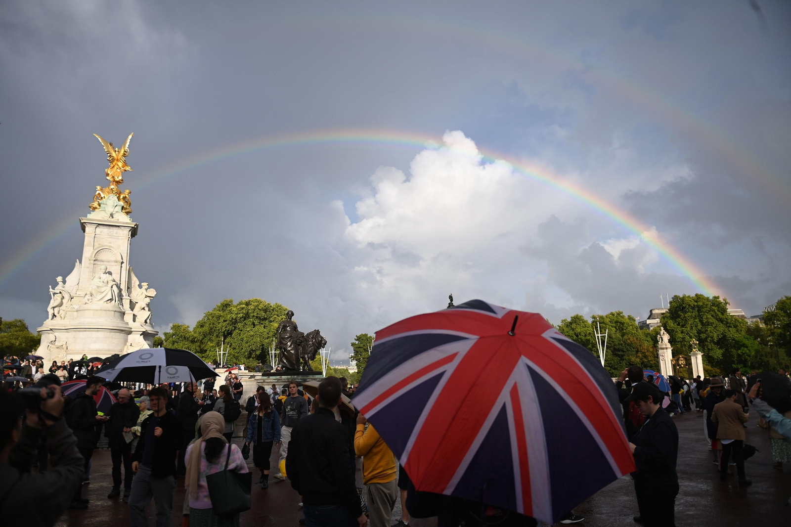 Un arcoiris aparece sobre el Queen Victoria Memorial mientras la gente se reúne frente al Palacio de Buckingham este jueves. Un arcoiris aparece sobre el Queen Victoria Memorial mientras la gente se reúne frente al Palacio de Buckingham este jueves.