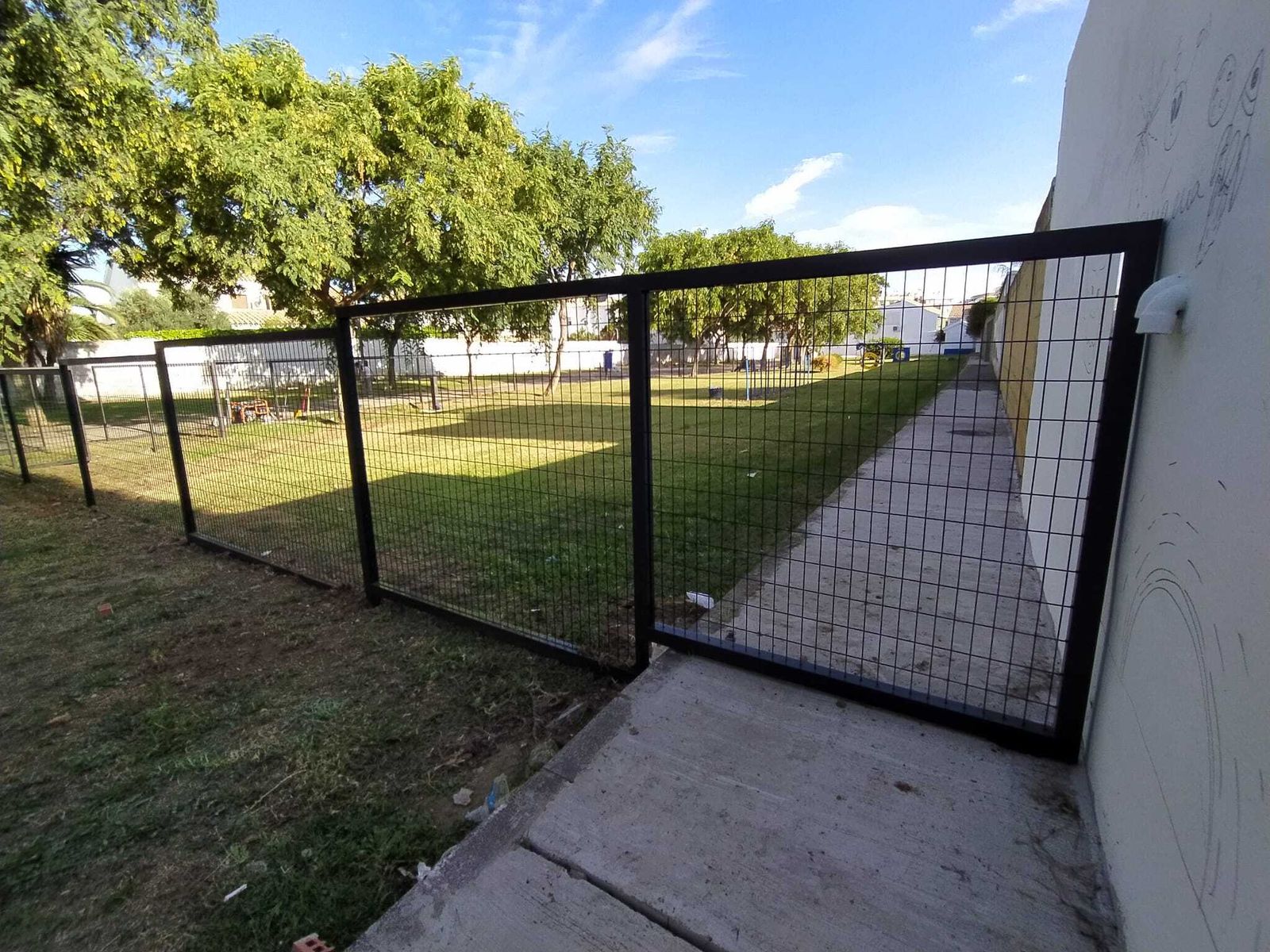 Vallas del parque canino, que cortan el paso de una acera y llegan hasta las fachadas de las viviendas utilizadas ahora como cerramiento lateral.