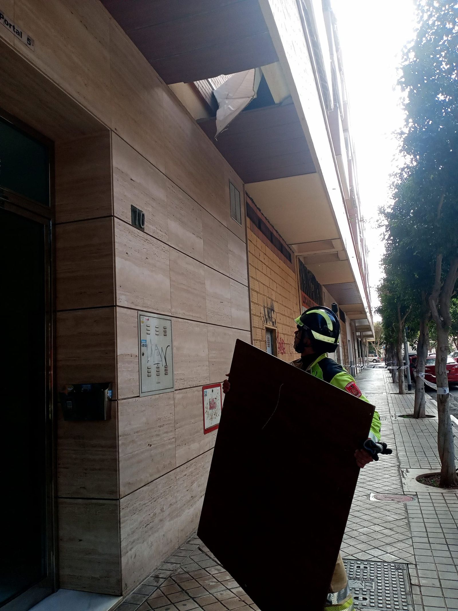 Los bomberos retiran elementos desprendidos por el viento en calle Peñón de la Reina, en Almería.