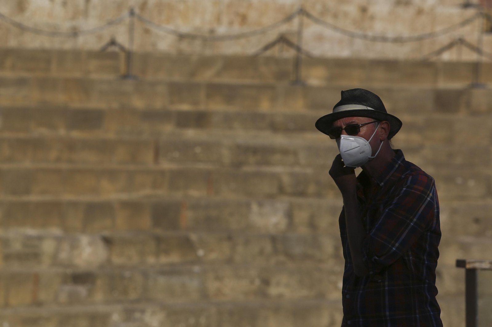 Un hombre con mascarilla pasa frente al Teatro Romano de Málaga. Un hombre con mascarilla pasa frente al Teatro Romano de Málaga.
