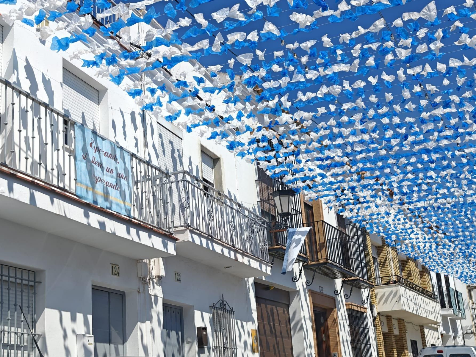 150.000 flores decorativas azules y blancas colocadas en la calle Mayor por la Romería.