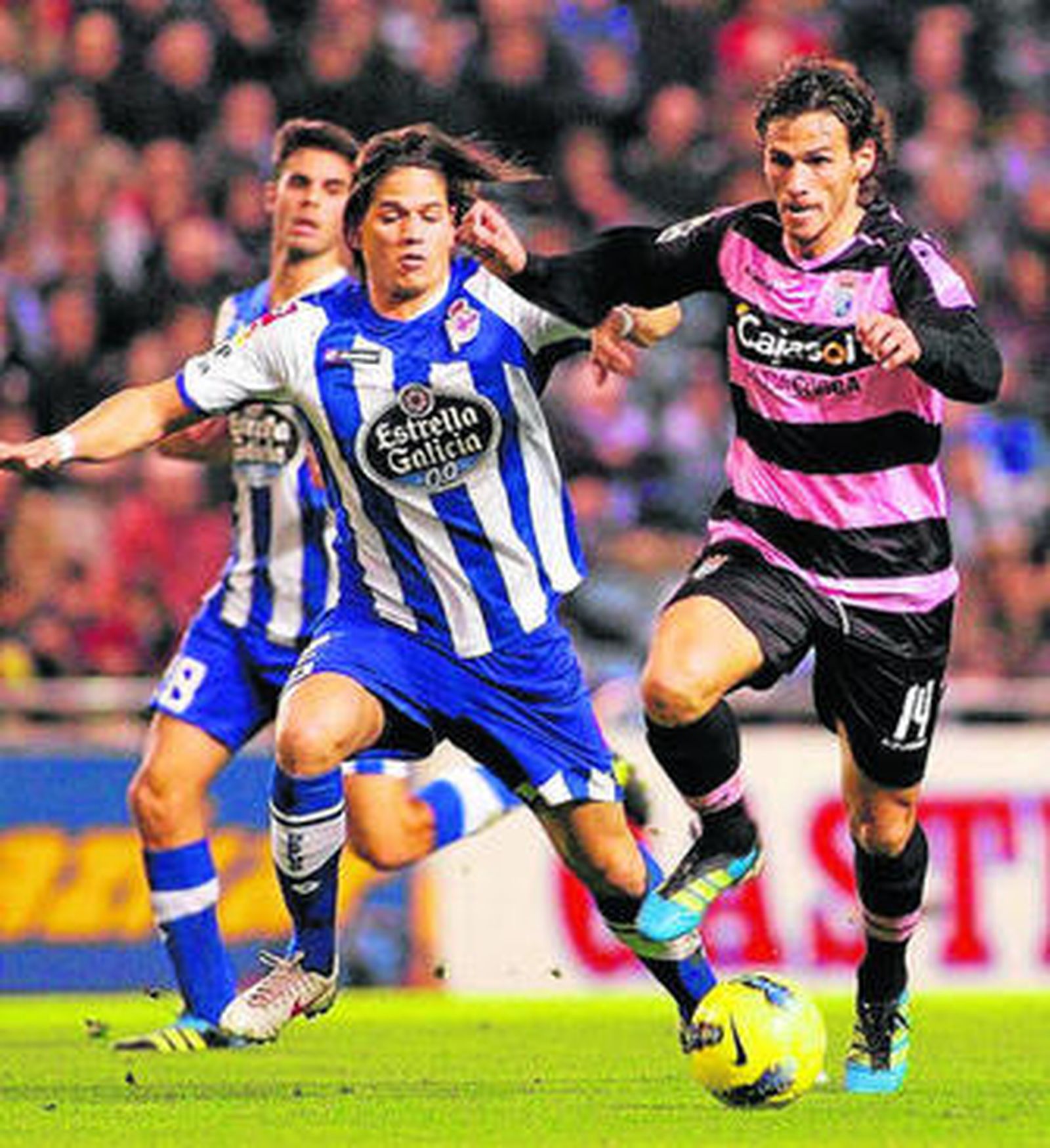 Capi (d) avanza con el balón controlado perseguido por un rival.
