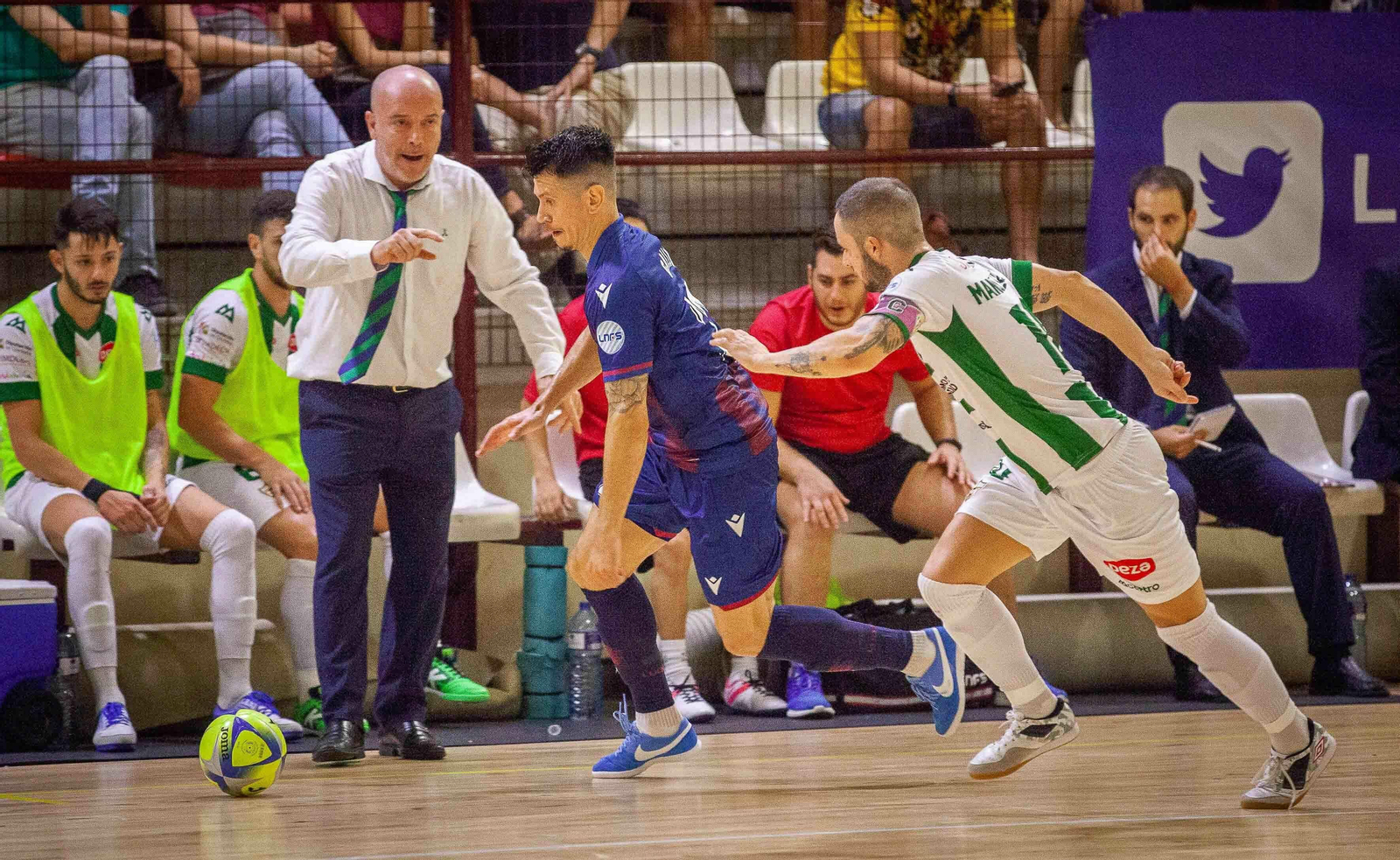 Macario sigue la evolución de una jugada entre Manu Leal y un rival desde su área técnica.