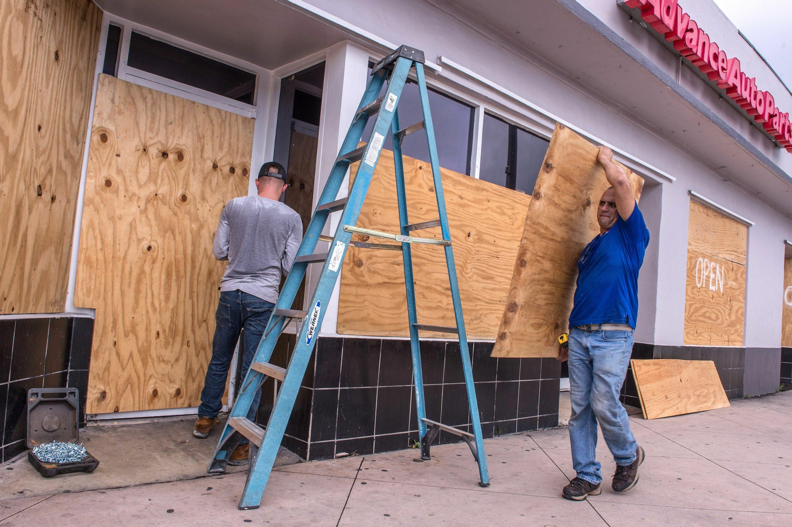 Empleados de una tienda de Miami Beach cubren el local con tablones de madera por la llegada del huracán Dorian.