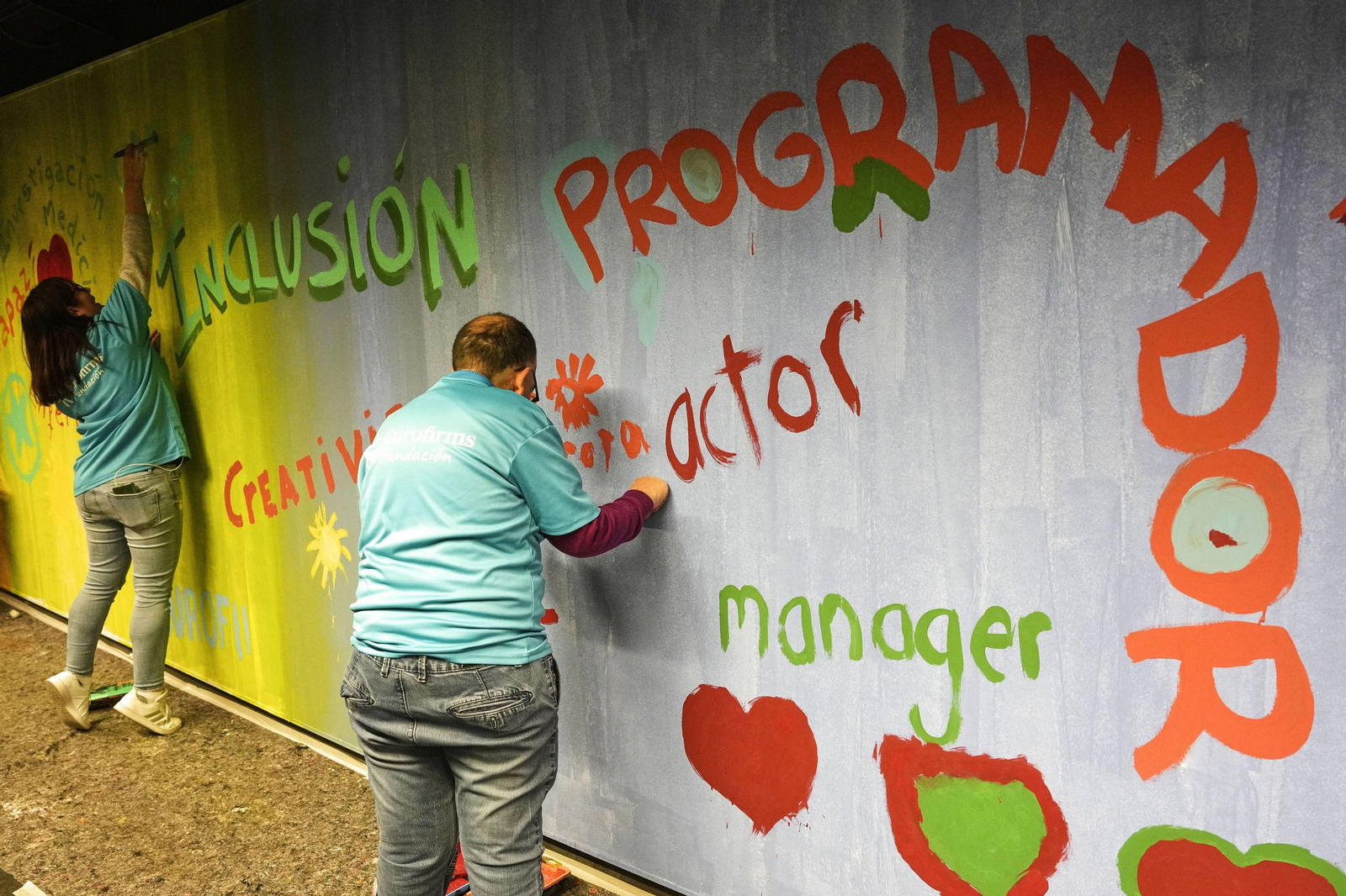 Personas con discapacidad participan en una pintada de un mural colectivo en una estación de metro de Barcelona.