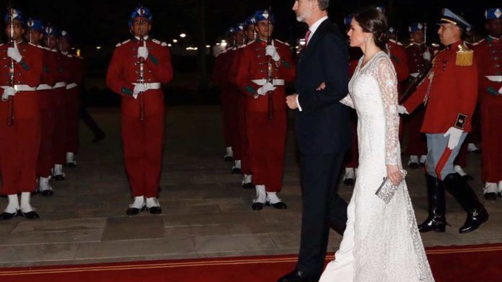 La reina con el traje de encaje blanco, pasa revista junto a su marido