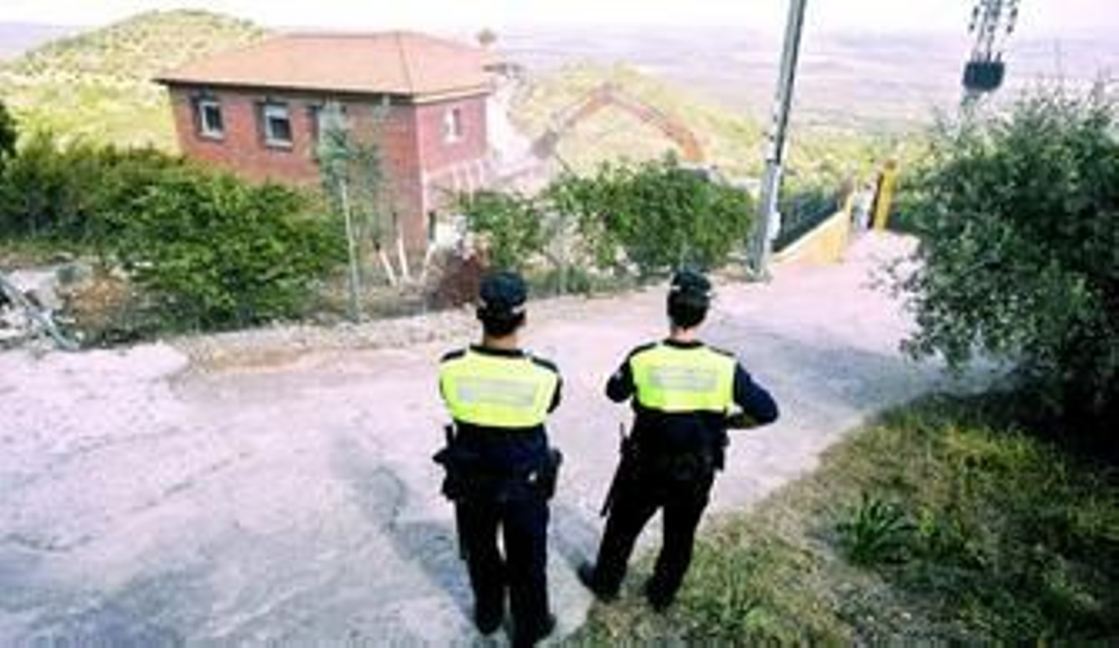 Dos agentes de la Policía Local contemplan el derribo de la parcela en la propiedad del Cerro de San Cristóbal.