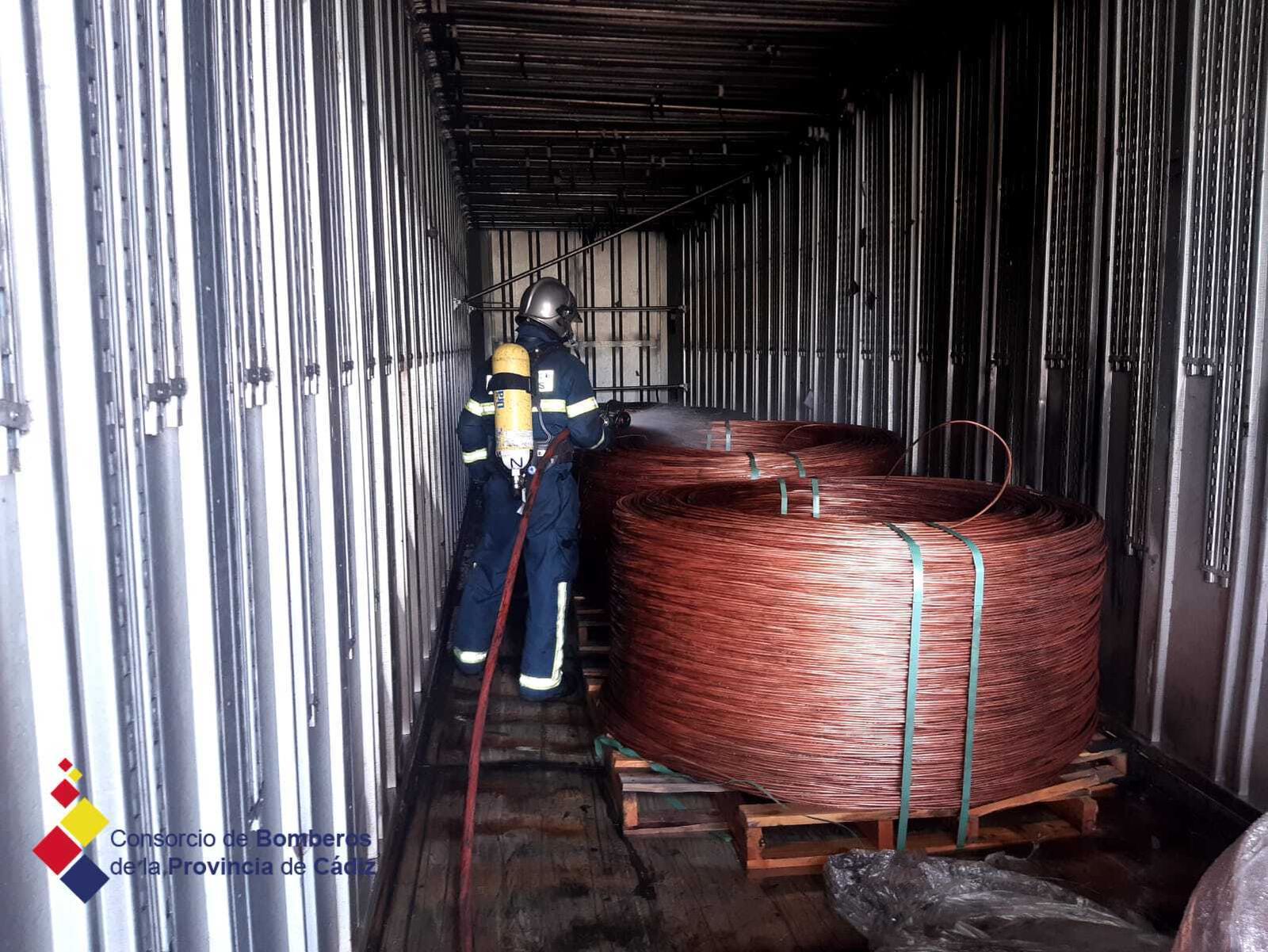 Un bombero enfría una de las bobinas de cobre que transportaba el camión siniestrado.