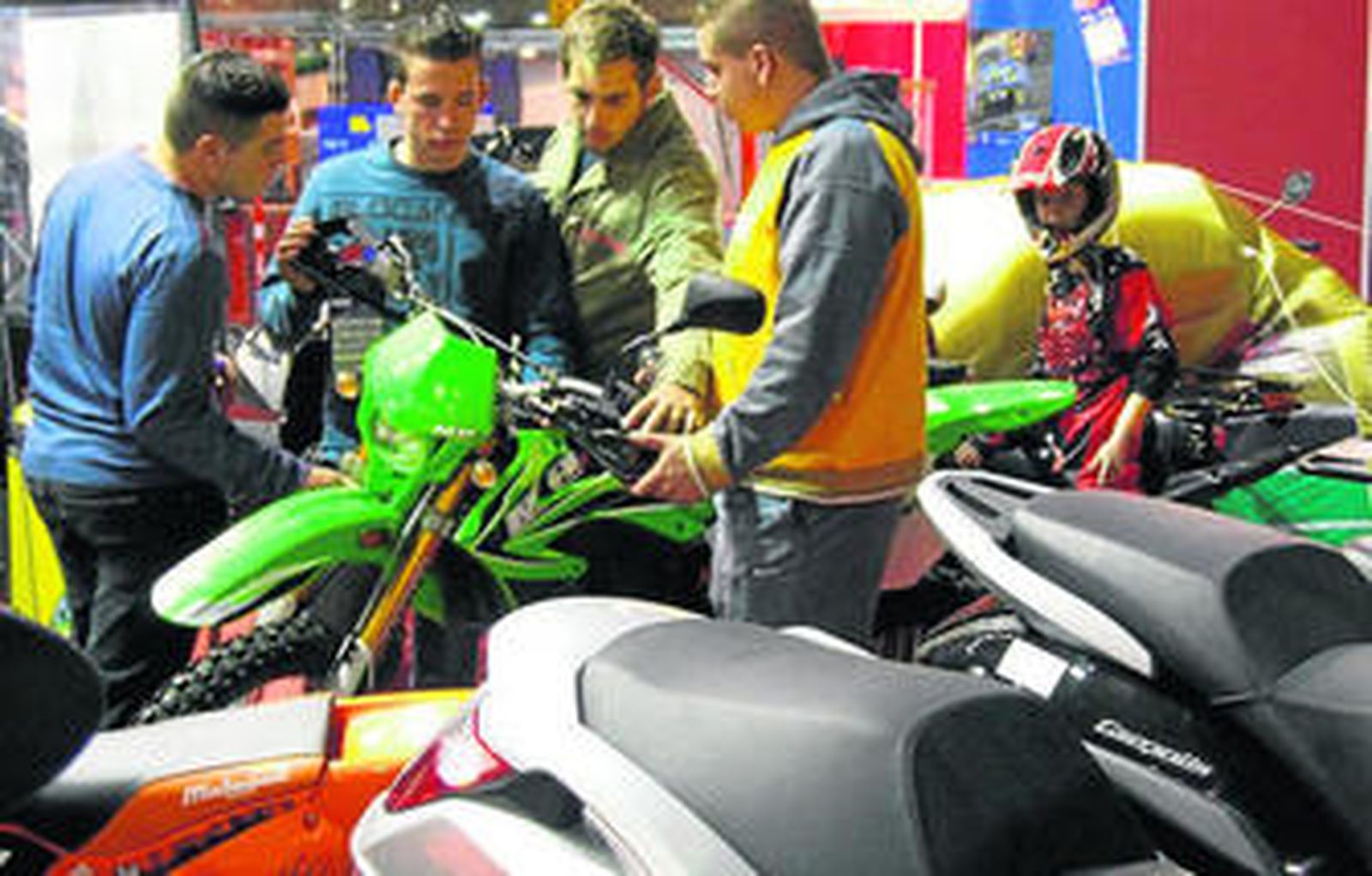 Unos jóvenes observan varios modelos de motocicletas en otra exposición similar.