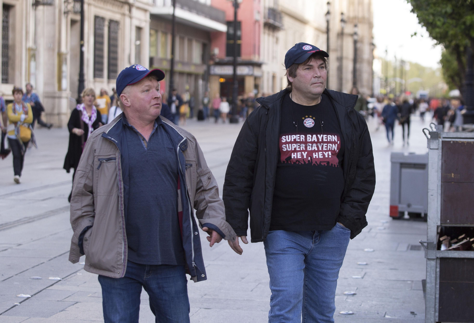 Dos aficionados del Bayern Múnich, perfectamente identificados por su camiseta y su gorra, pasean por la Avenida de la Constitución.