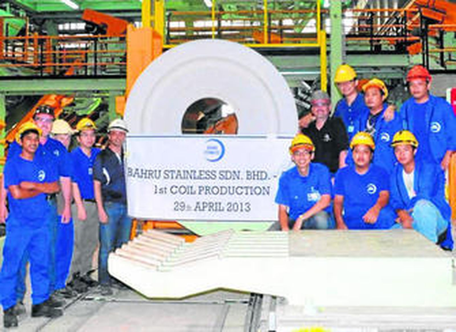 Trabajadores de la factoría de Malasia posan con la primera bobina salida de la fábrica.