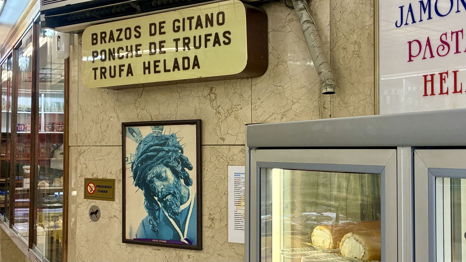 La imagen del Señor en el interior de una confitería, junto al rótulo y la vitrina de los brazos de gitano.