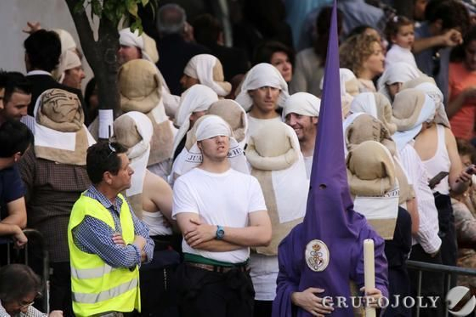Un grupo de costaleros de María Santísima de la O, ataviados con el costal y casi cegados por él, espera en la calle Larga a que llegue el paso para proceder al relevo.

Foto: Manuel Aranda