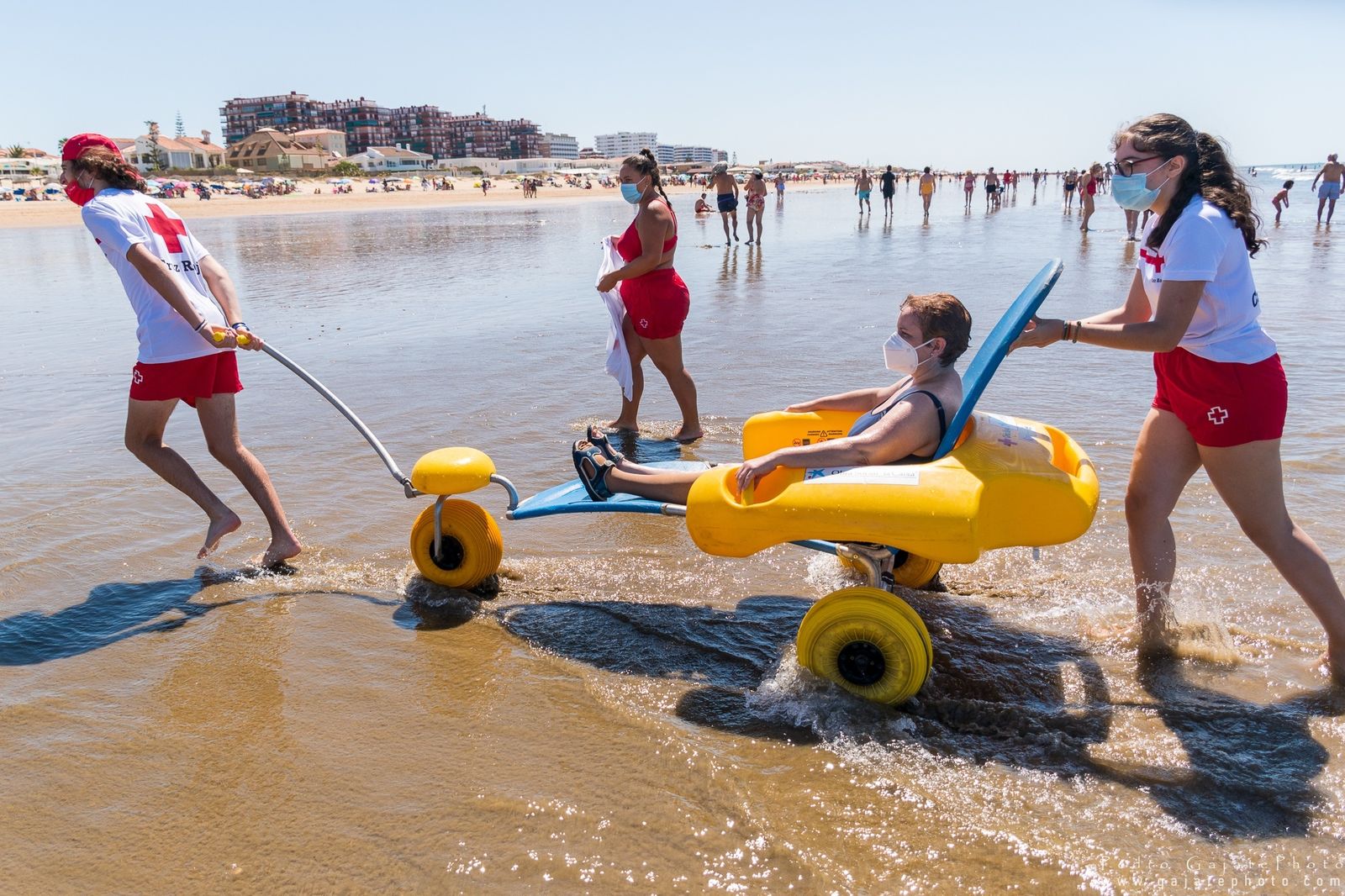 Los voluntarios de la Cruz Roja Huelva ayuda a una persona con discapacidad para disfrutar de la playa