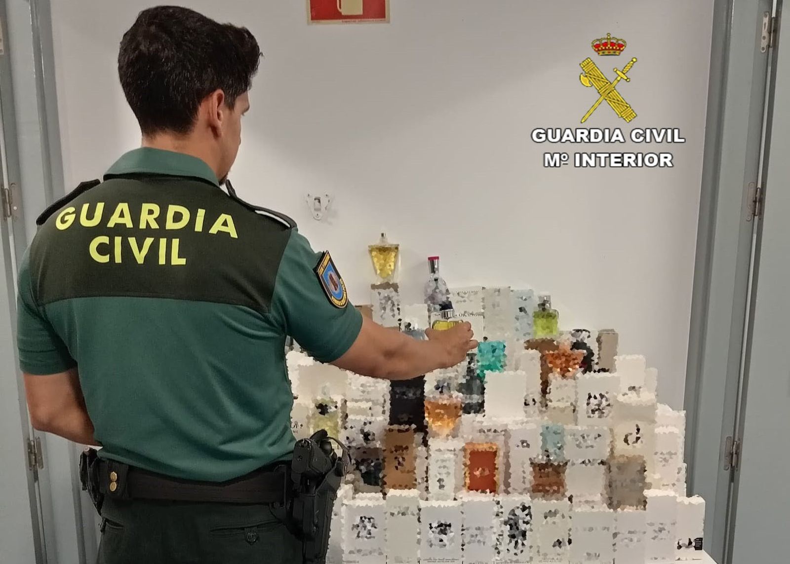 Un agente junto a los perfumes incautados en el Puerto de Huelva.