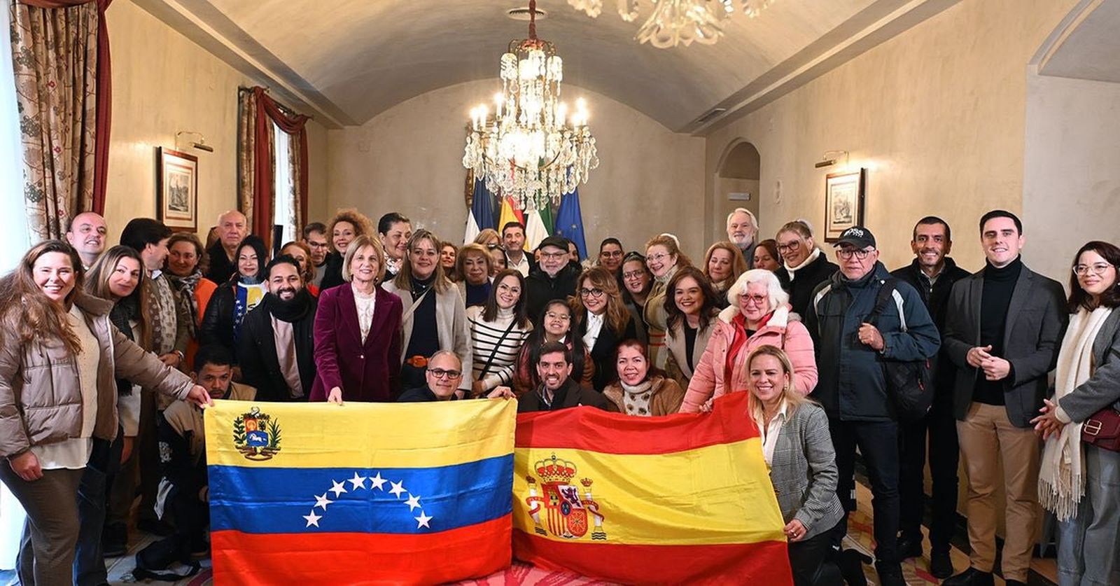 Yessica Quintero, sujetando la bandera española, junto a miembros de la comunidad venezolana en Jerez y miembros del gobierno local.