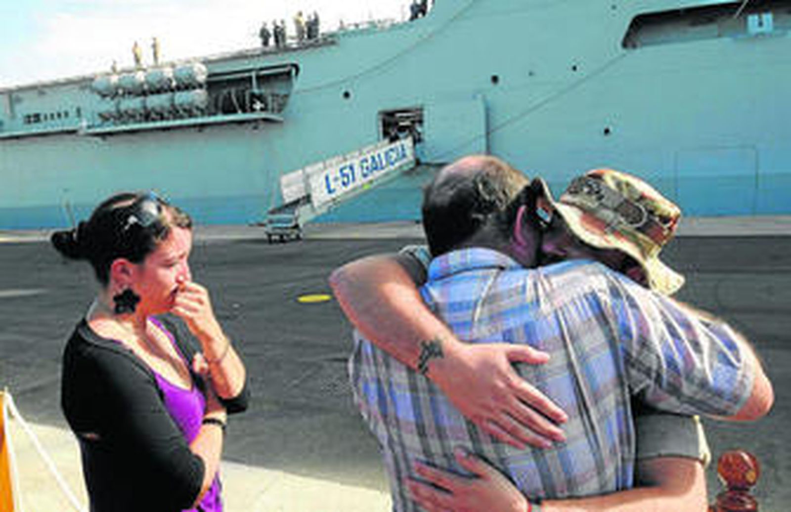 Uno de los marinos se despide con un fuerte abrazo de sus familiares, con el buque 'Galicia' detrás antes de zarpar.