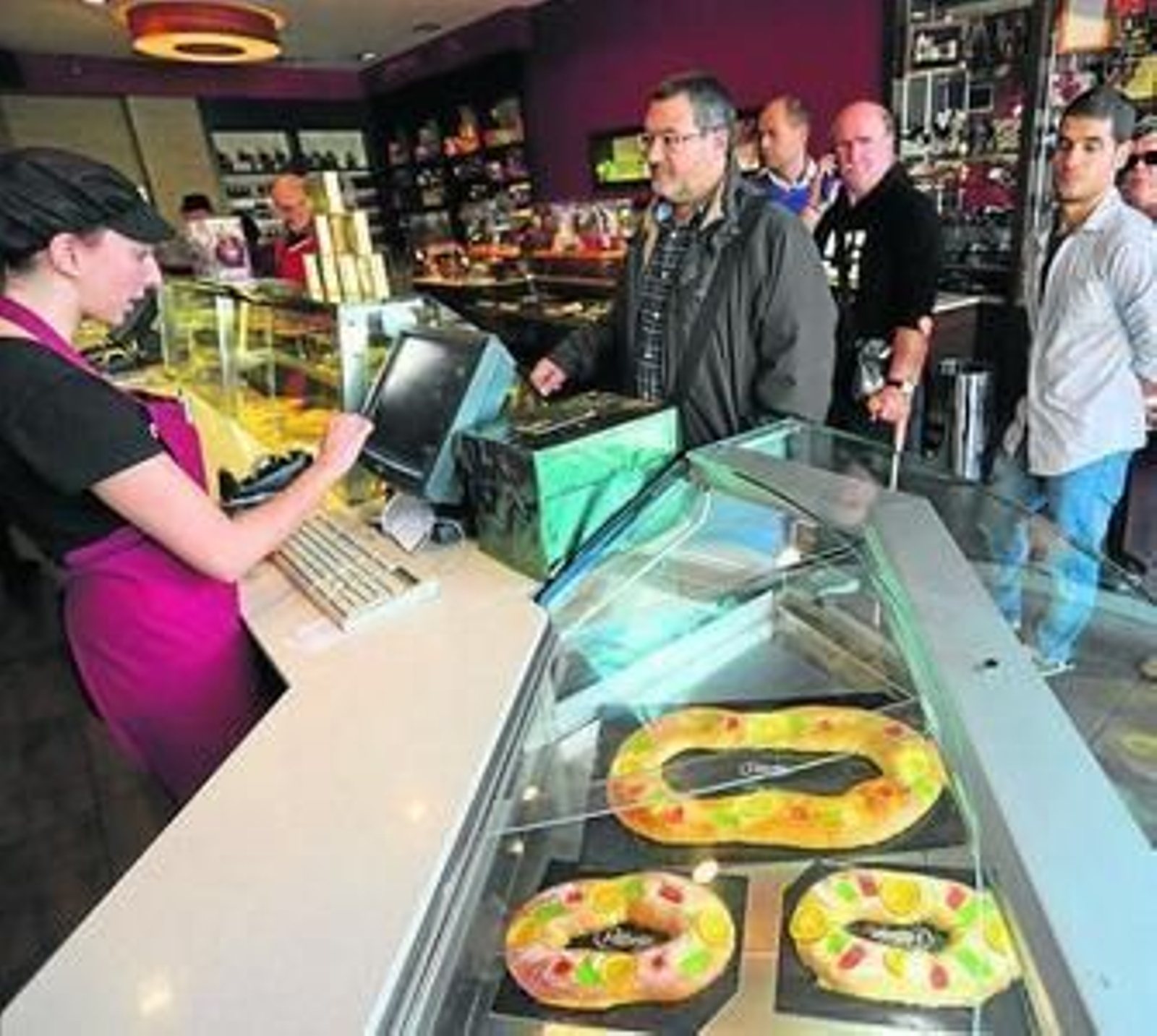 Varias personas hacen cola ayer para comprar un rosco.