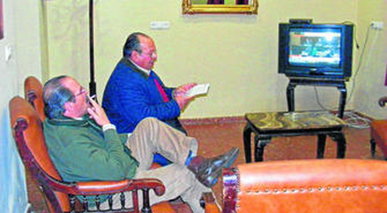 Dos miembros del club fuman mientras ven la tele.