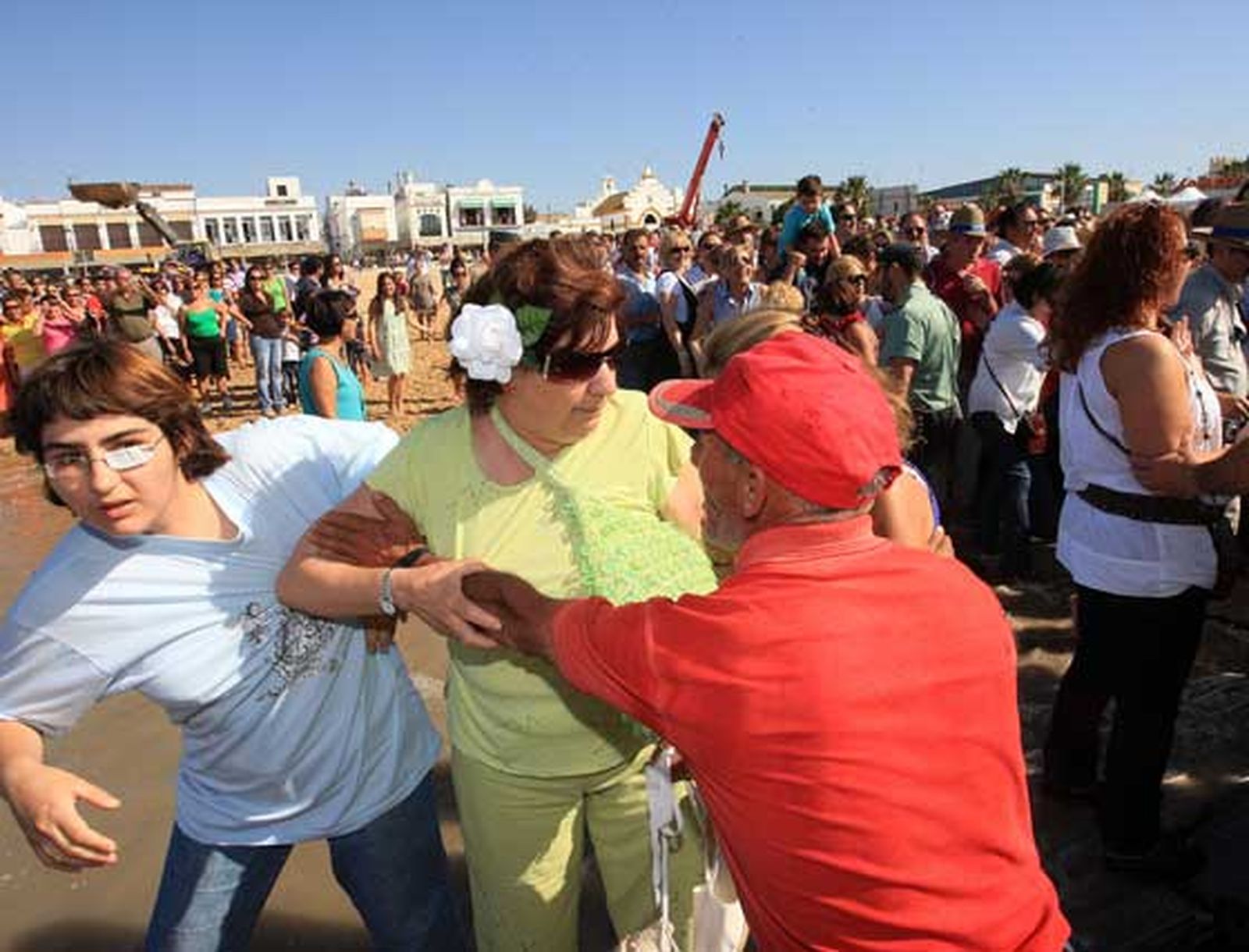 Un barquero forcejea con dos rocieras que, pese a las indicaciones, intentan embarcar junto al Simpecado.

Foto: Juan Carlos Toro