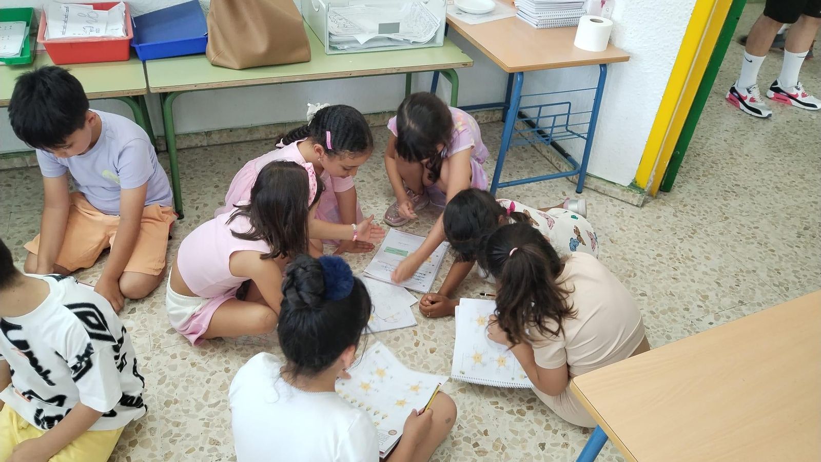 Los niños trabajan en el suelo para refrescarse ante las elevadas temperaturas en las aulas.