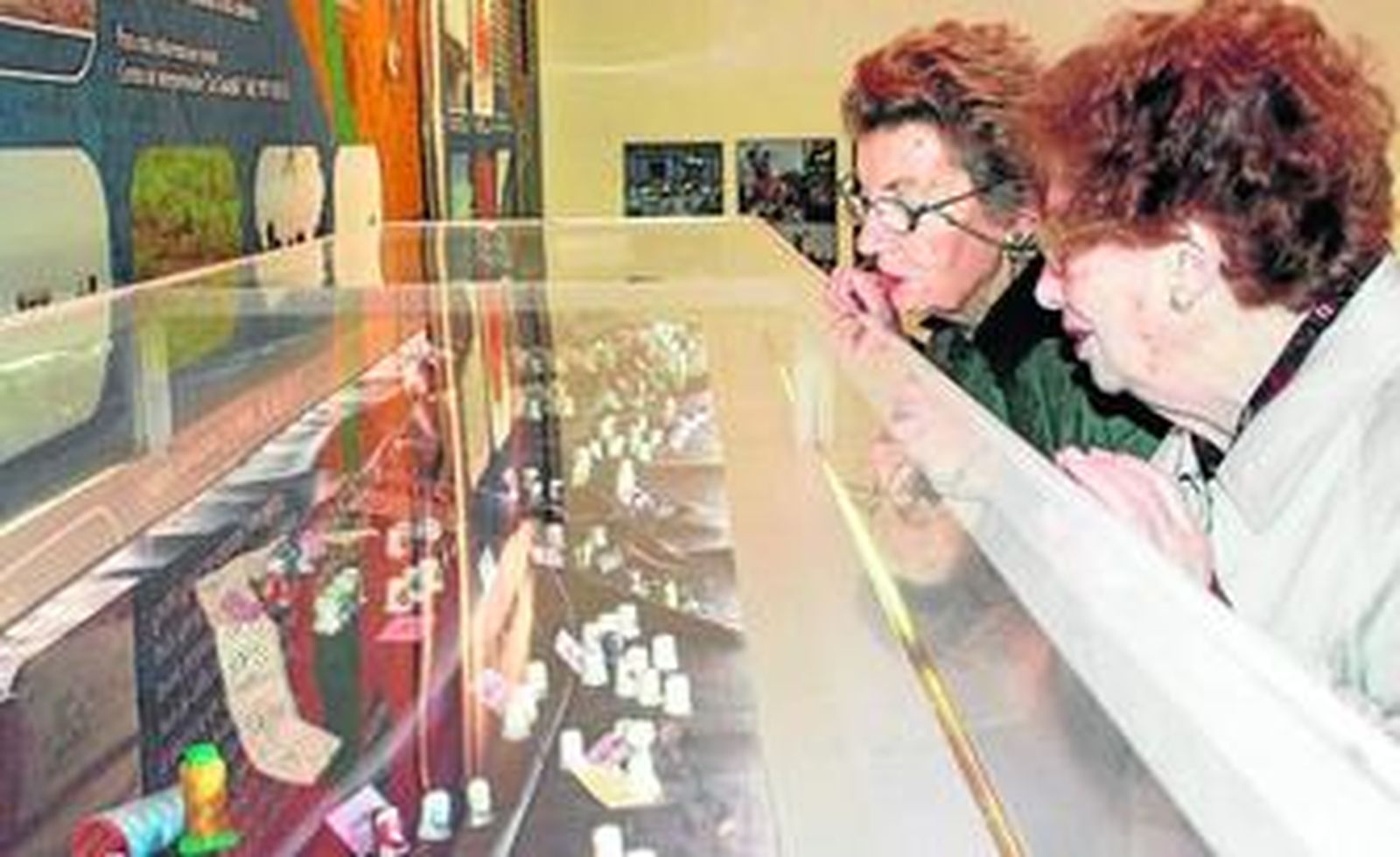 Dos señoras observan atentas la amplia exposición de dedales abierta en Puerta del Atlántico.