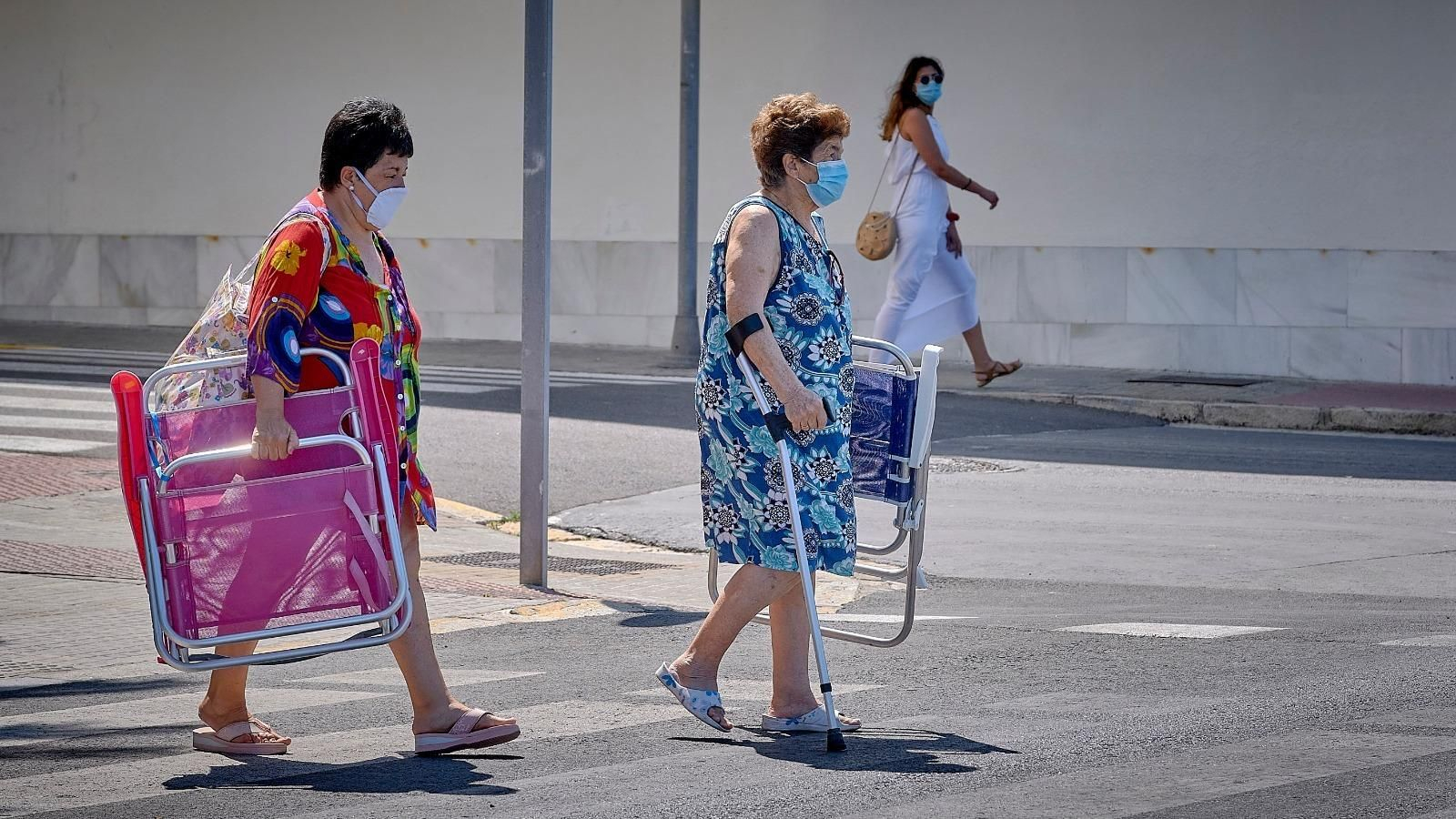 Dos señoras que se dirigen a la playa con sus mascarillas.