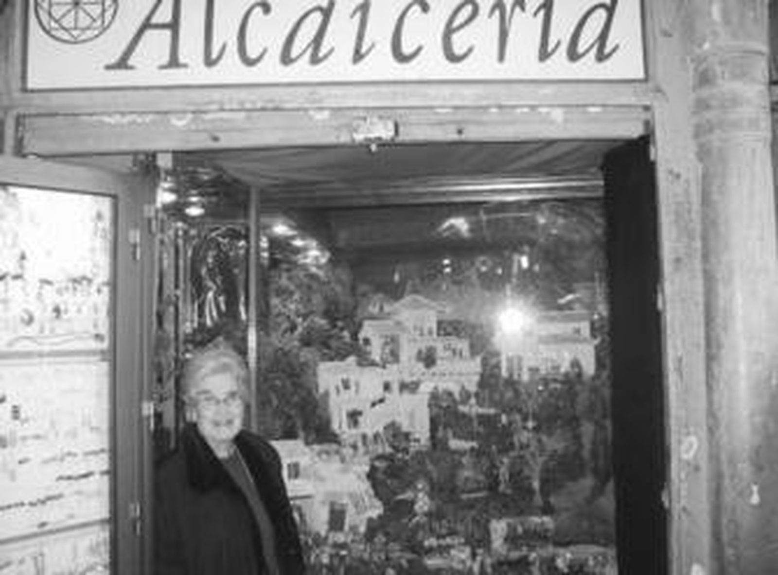 Charo Mariscal, en la fotografía superior, posa en la puerta de su tienda de la Alcaicería, donde durante más de 40 años, las figuritas del tradicional belén acuden a su cita de Navidad. Debajo, dos representaciones características de estas fechas: la que instala la Caja Rural y la que monta la joyería en la calle Reyes Católicos, un clásico de la Navidad granadina.
