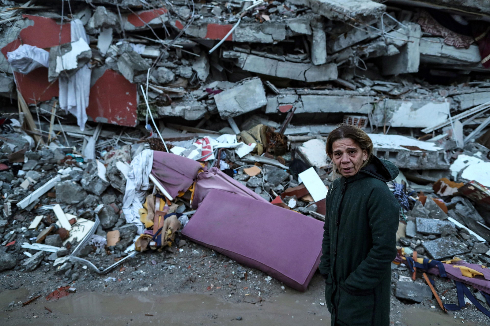 Una mujer llora ante los restos de un edificio.