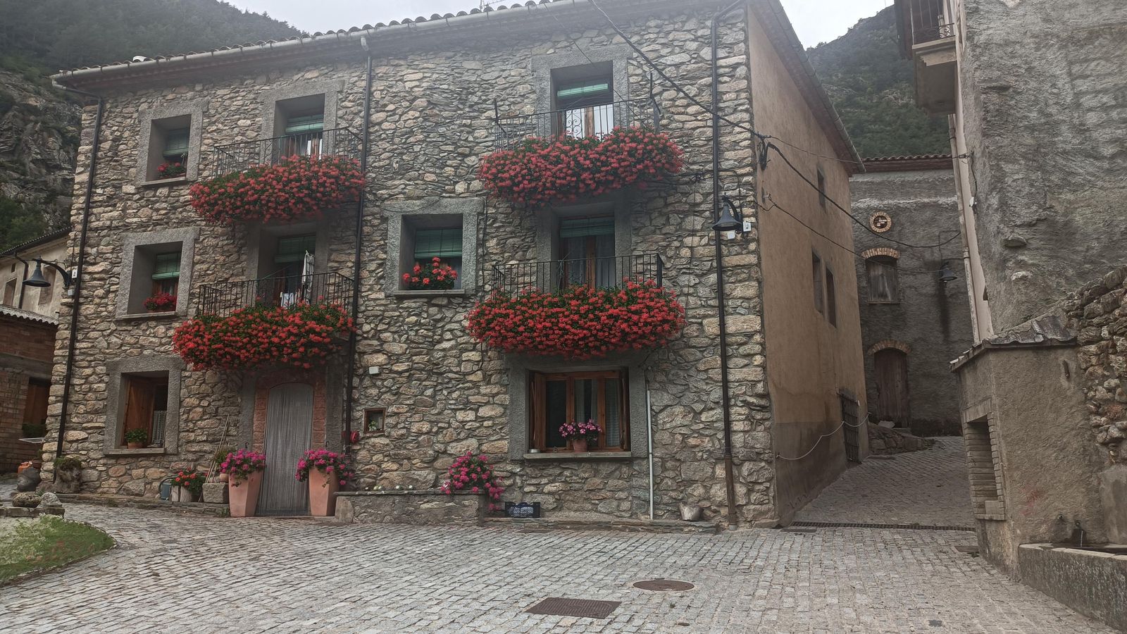 Casa de Forcat. El contraste de la piedra y las coloridas flores llamará nuestra atención.