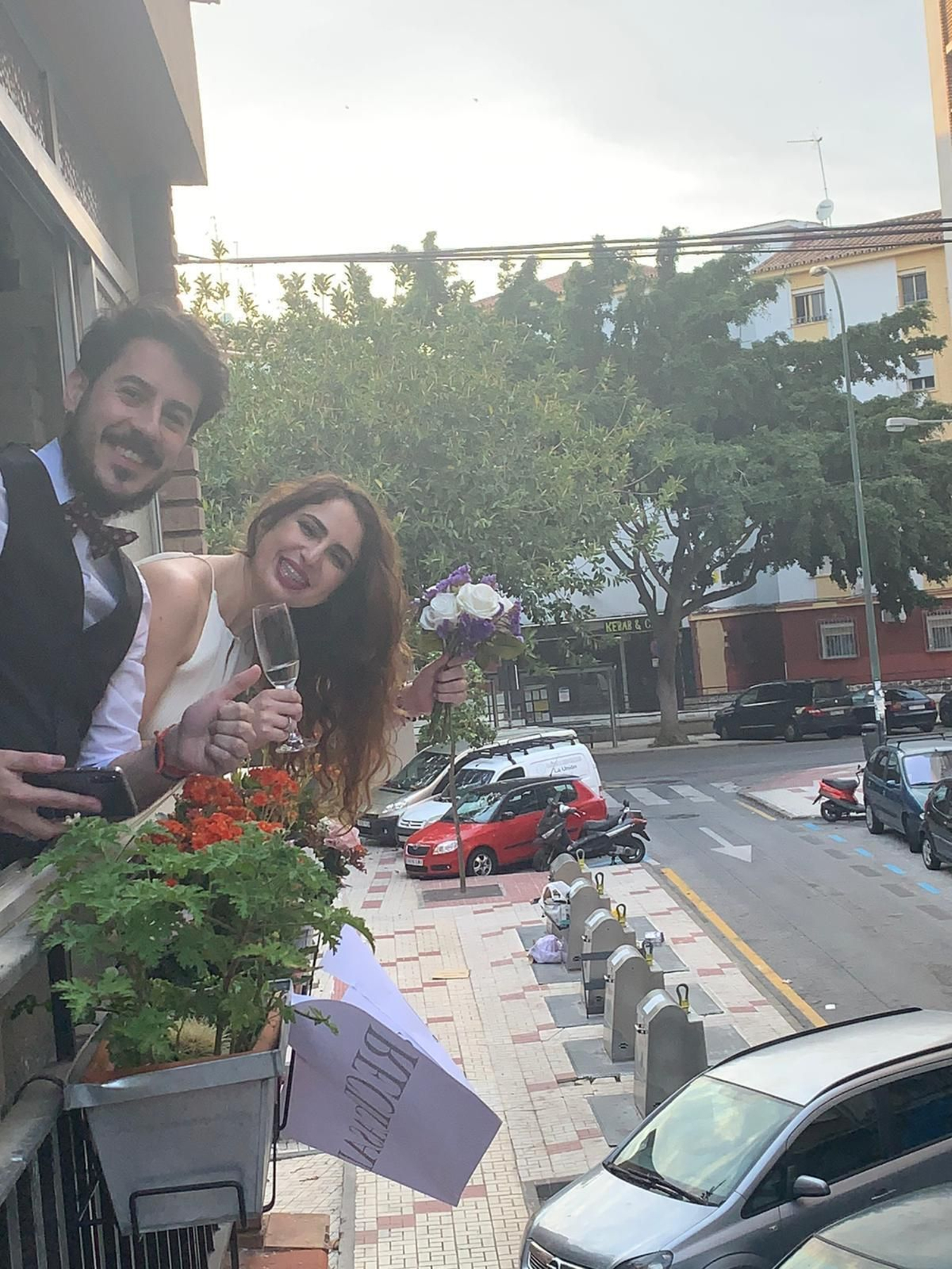 Juan Carlos y Lali posan en el balcón, champán y ramo en mano.