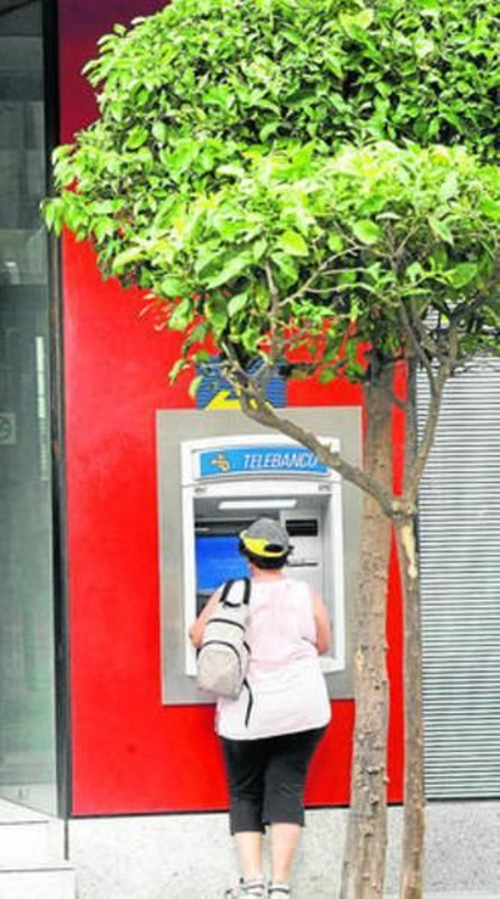 Una mujer saca dinero de un cajero automático.
