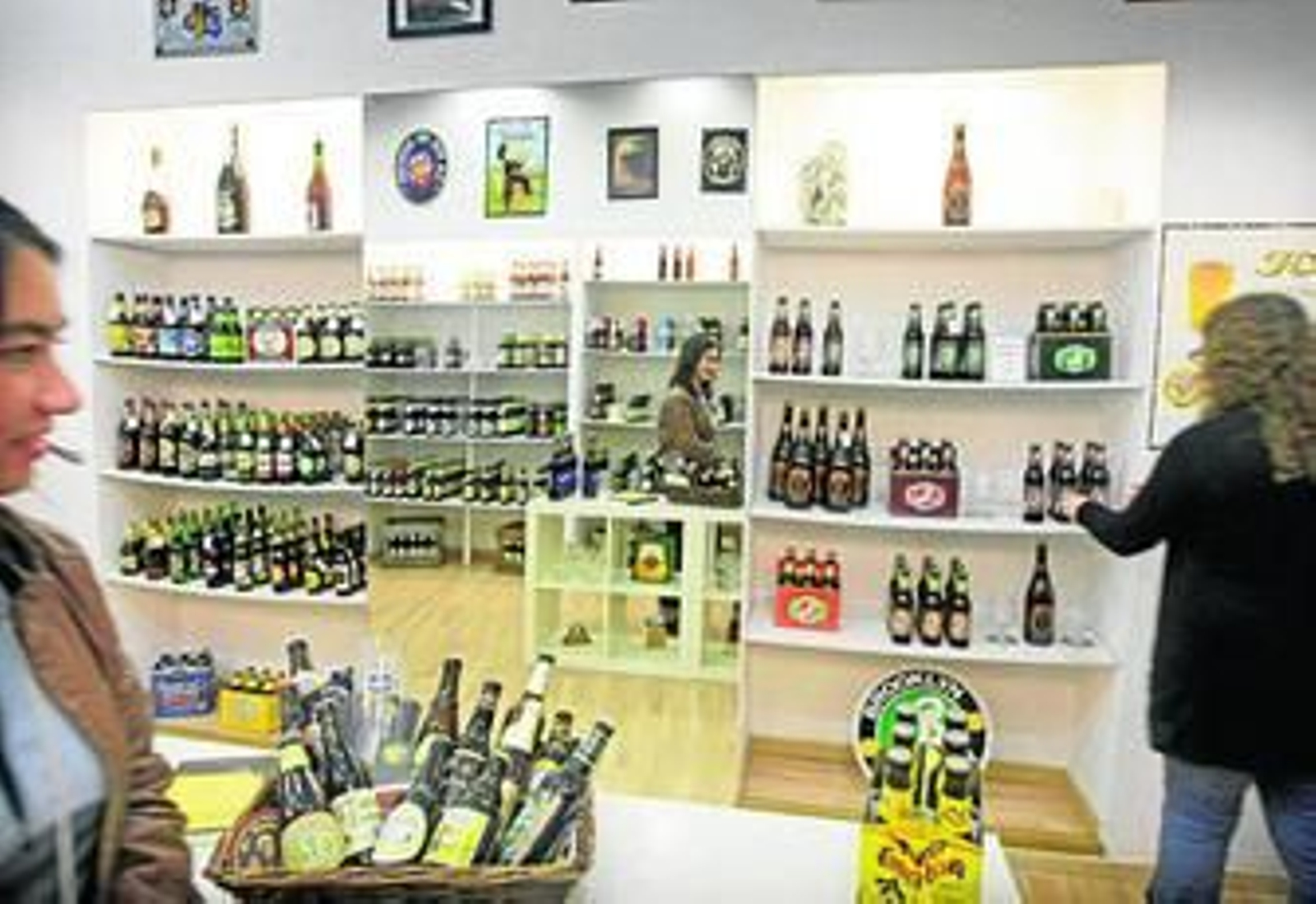 Varios turistas observan la variedad de cervezas de la tienda Gades Beer.