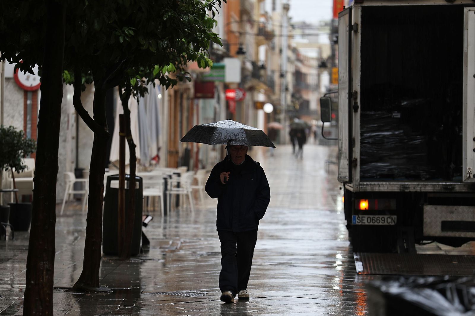 Un señor se resguarda de la lluvia en Huelva.