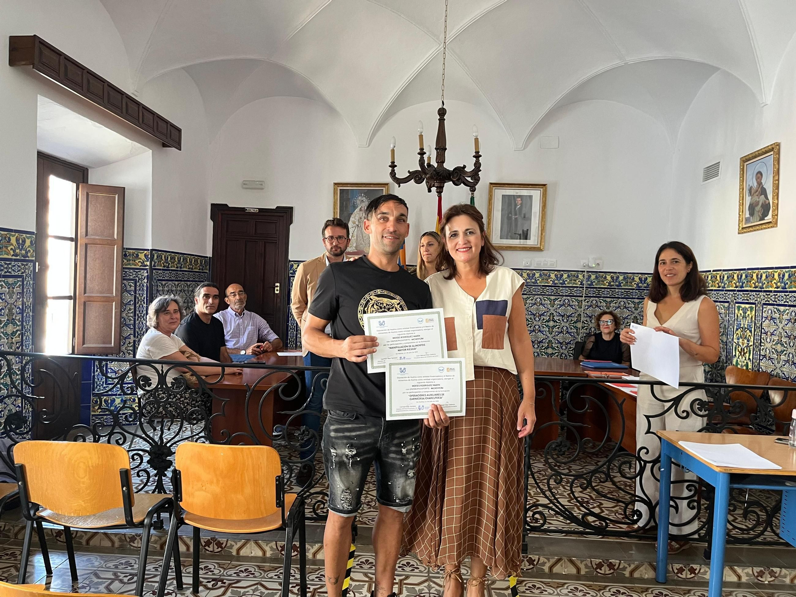 Uno de los alumnos con su diploma junto a Carmen Díaz.