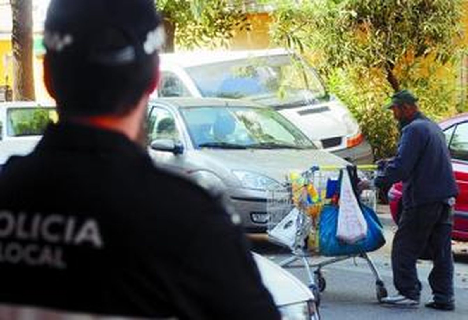 1. Un hombre empuja un carro de la compra cargado de chatarra bajo la mirada de un agente de la Policía Local, este jueves en la calle Candelería. 2. Dos vecinas pasan por un muro ensuciado por múltiples pintadas. 3. Unos niños juegan en el colegio Blanca Paloma, que ha sido asaltado tres veces en la primera quincena de septiembre. 4. Ángel Silva, frutero de la calle Candelería, dialoga con unas clientas a la puerta de su tienda.