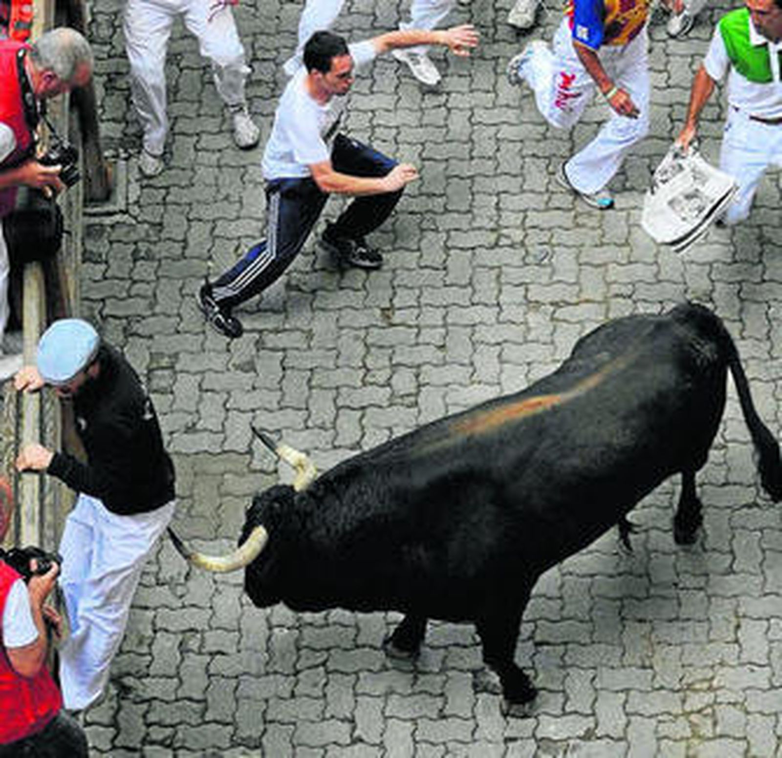 Un corredor, a punto de ser corneado, intenta saltar el vallado.