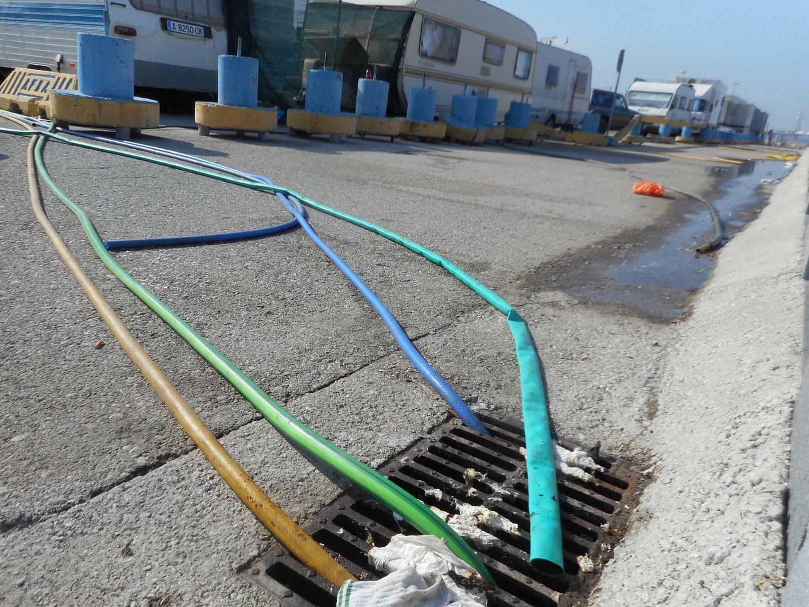 Varias mangueras conectadas a una alcantarilla y, al fondo, una sin enganchar.