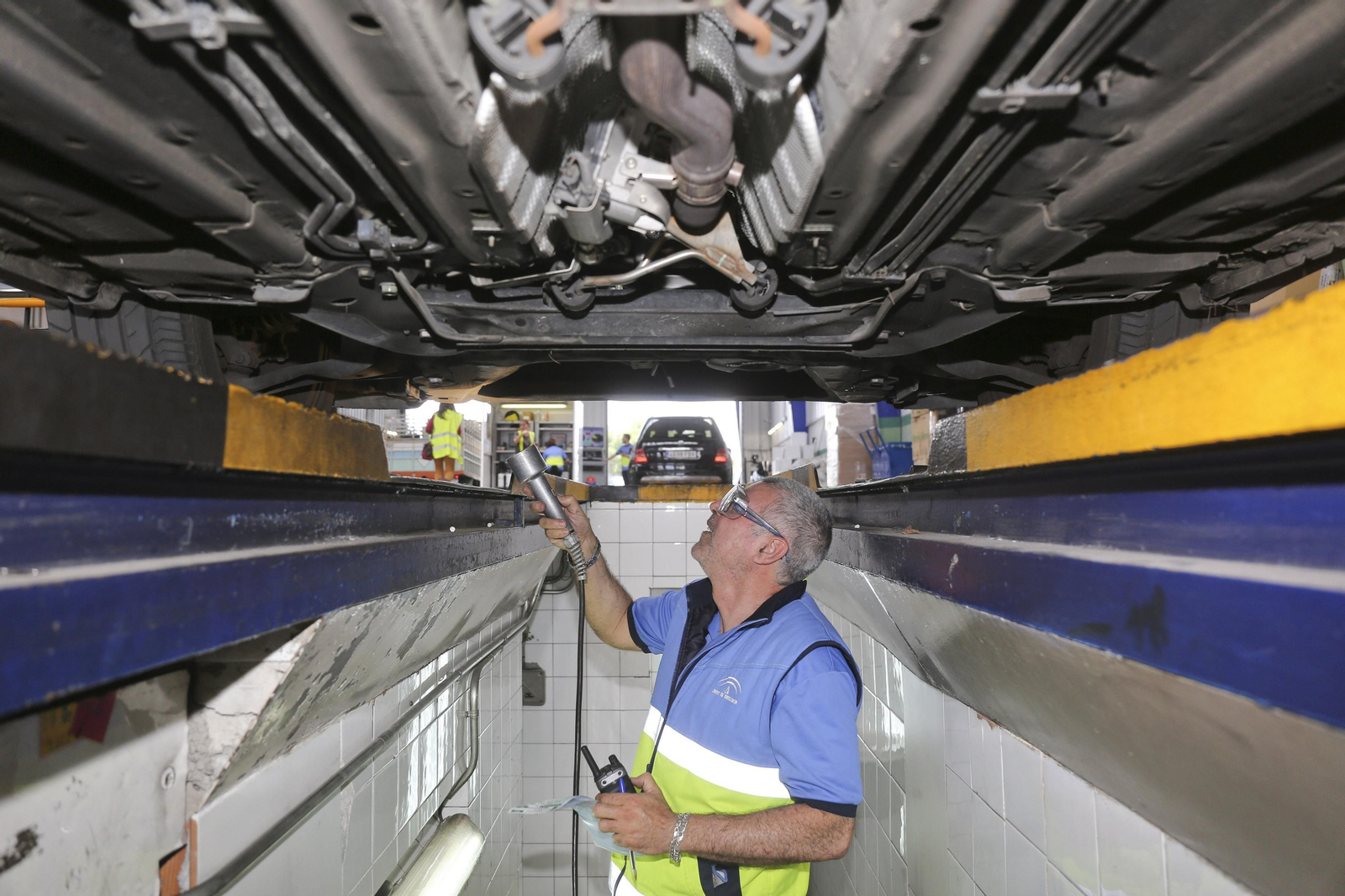 Un trabajador de una estación ITV malagueña revisando los bajos de un vehículo.