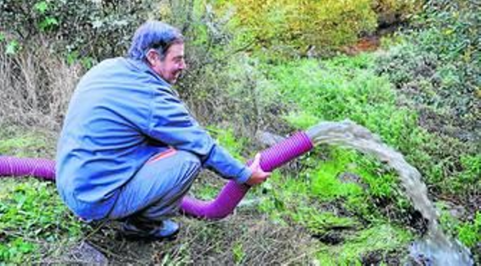 Un técnico municipal sostiene la manguera por la que está desaguando el embalse de Santa María.