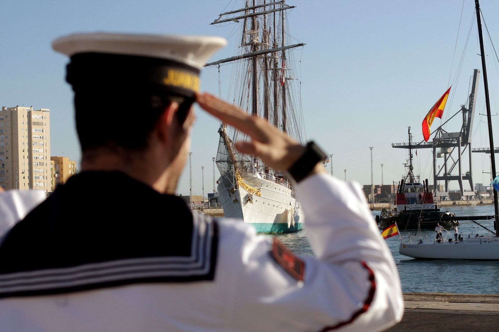 El buque escuela 'Juan Sebastián de Elcano' llega al  muelle de Cádiz ante el saludo de un marinero.