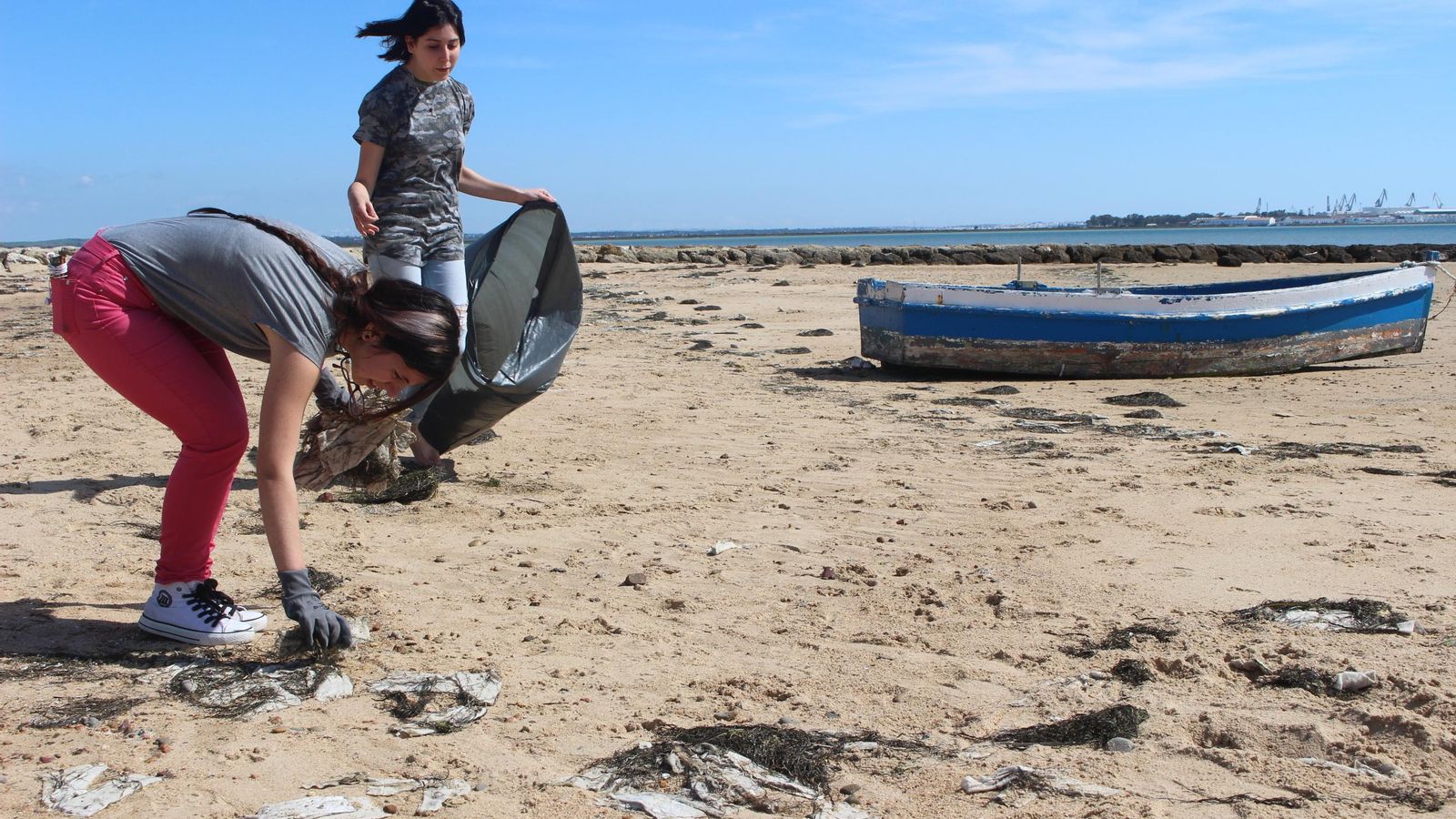 Dos jóvenes limpian la playa de La Cachucha