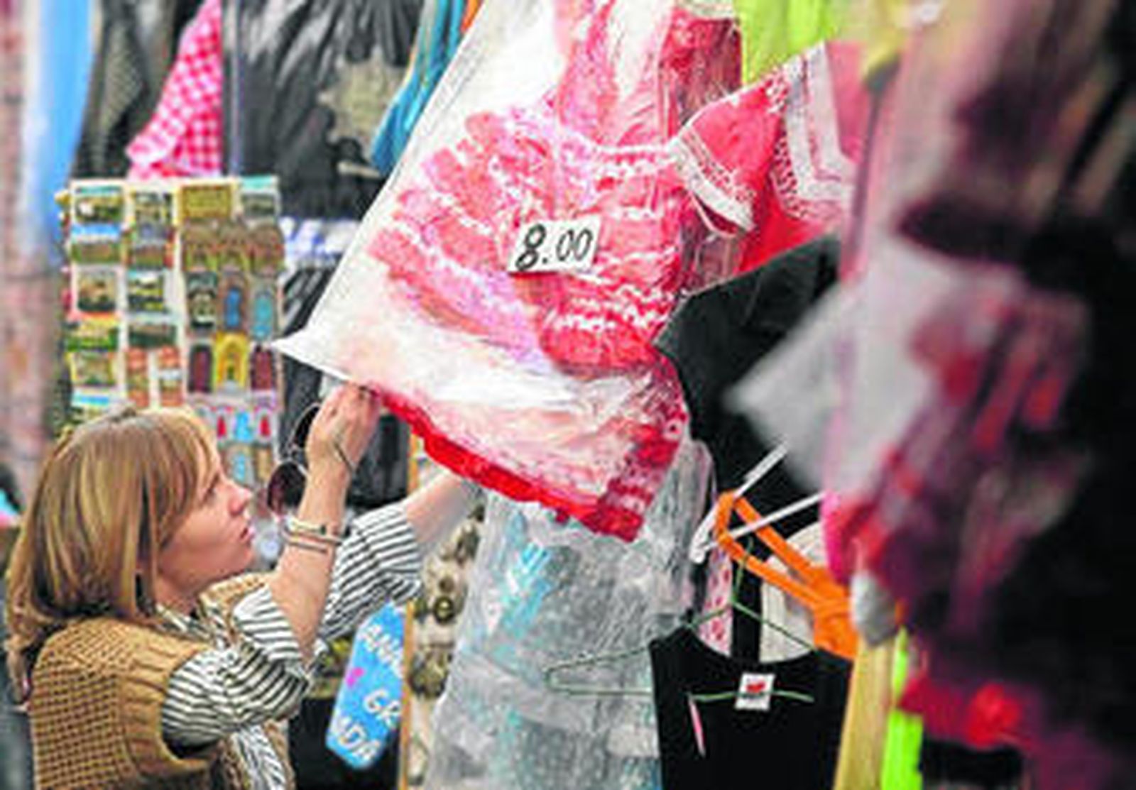 Una turista ojea un vestido en una tienda de souvenirs.
